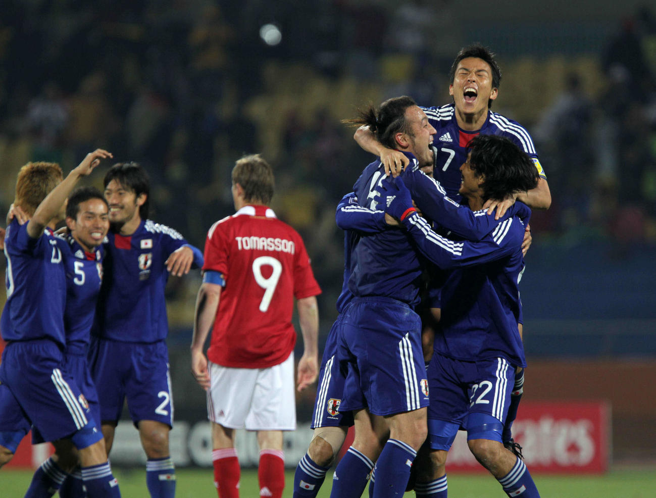 W杯南アフリカ大会1次リーグE組　日本対デンマーク　決勝トーナメント進出を決めた日本代表の、右からDF中沢佑二、MF長谷部誠、DF田中マルクス闘莉王は抱き合って喜ぶ。左端からMF稲本潤一、DF長友佑都、MF阿部勇樹。中央9番は敗退でガックリのデンマークFWトマソン（2010年06月24日）