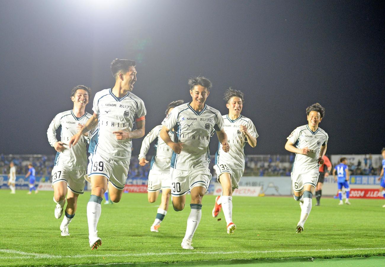 後半、勝ち越しゴールを決め、応援席に向かって走る札幌の選手たち。左から2人目がゴールを決めた小林