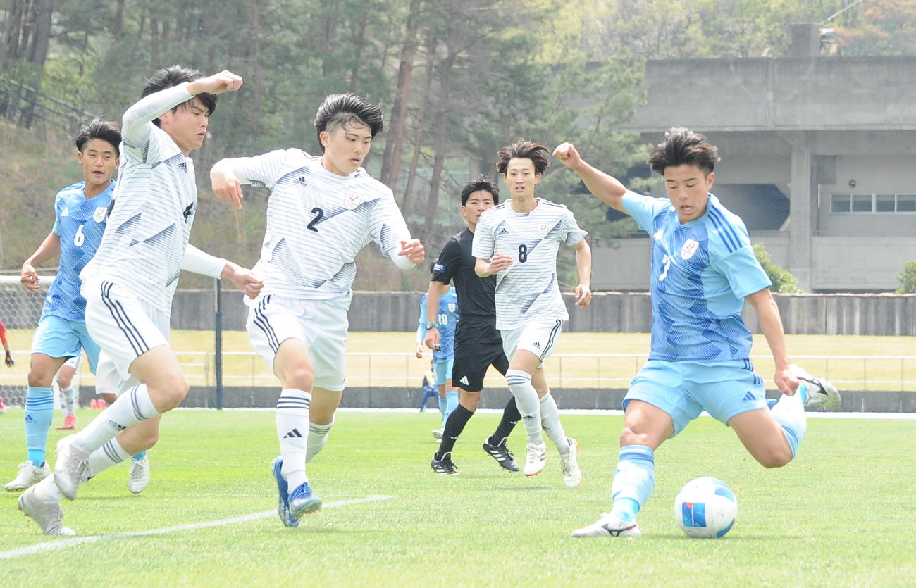 相手に囲まれながらクロスを上げる新潟医療福祉大・田沢（右）