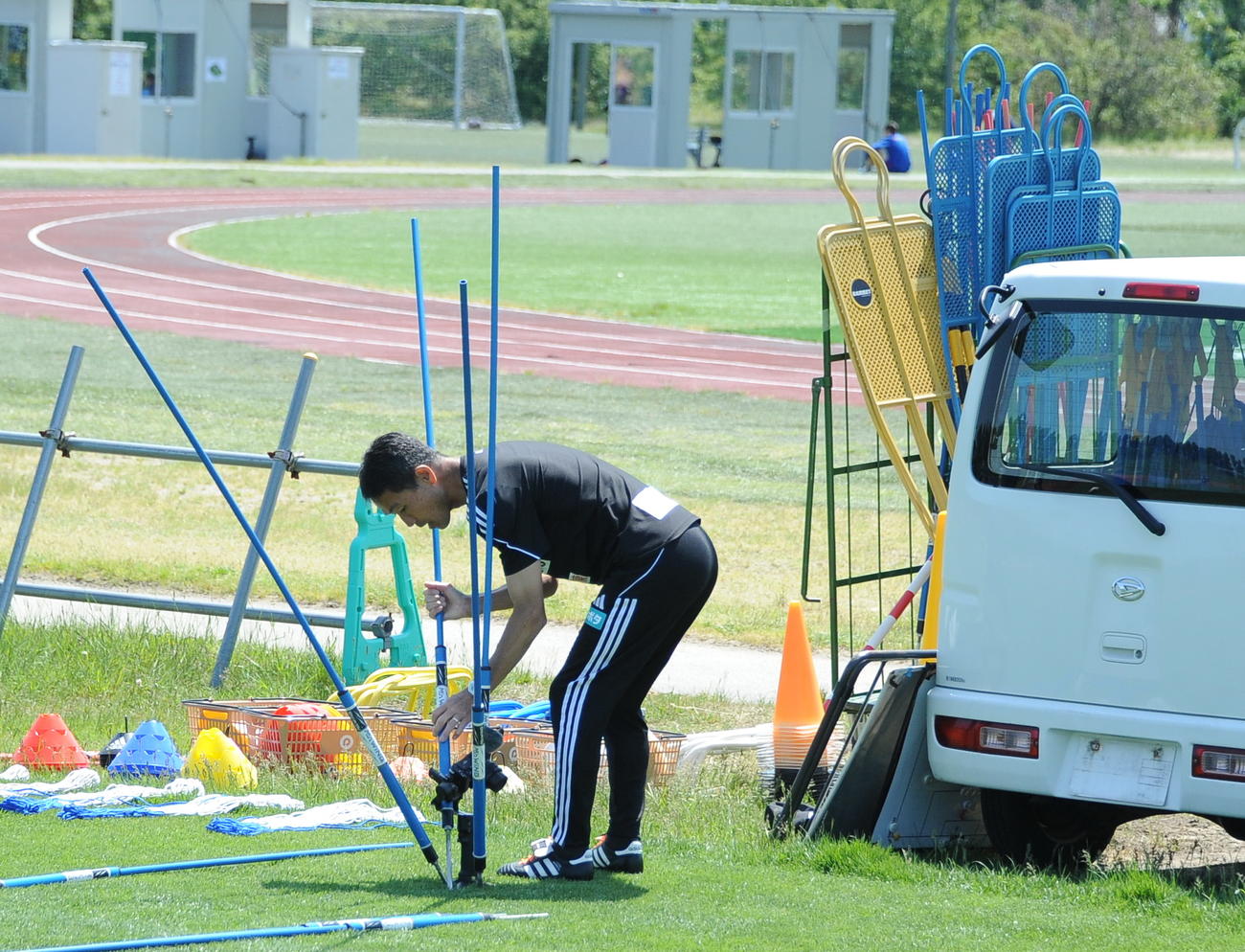 広報部がピッチ脇に設置したカメラを回収したポールで囲む松橋監督