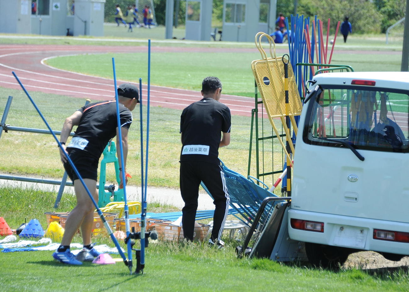 倒れたダミー人形を片付ける松橋監督（右）
