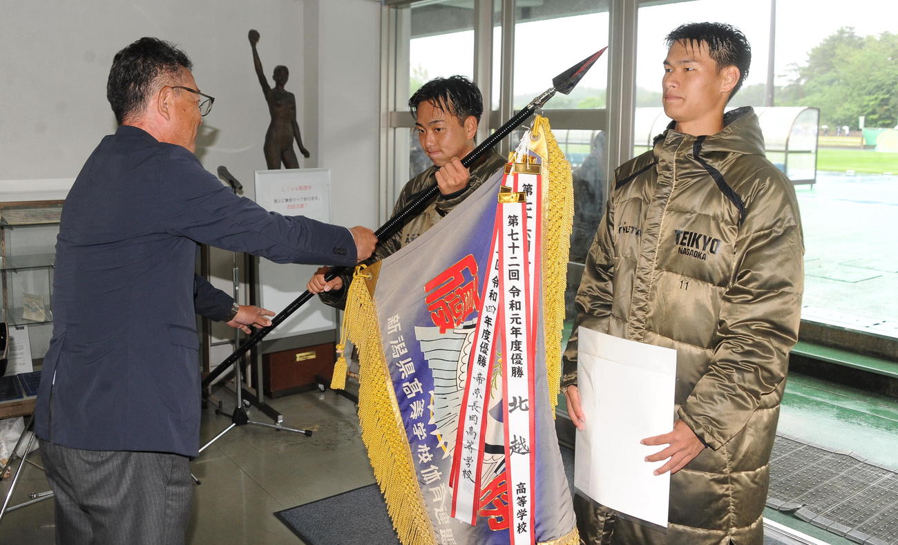 大会3連覇を達成し、優勝旗と賞状を受け取る帝京長岡・山本主将（右）と水川