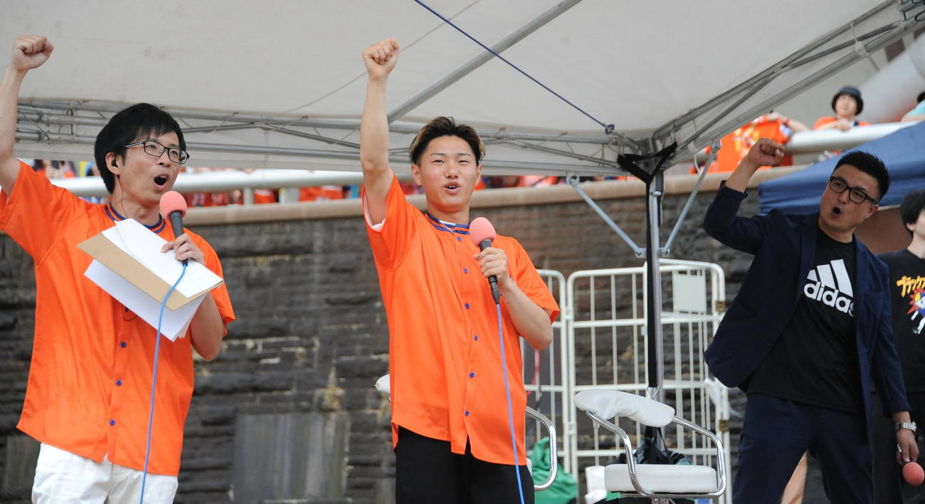 新潟－川崎F戦前、スタジアムの外で行われたトークショーに参加し、勝ちどきを上げる元新潟三戸（中央）
