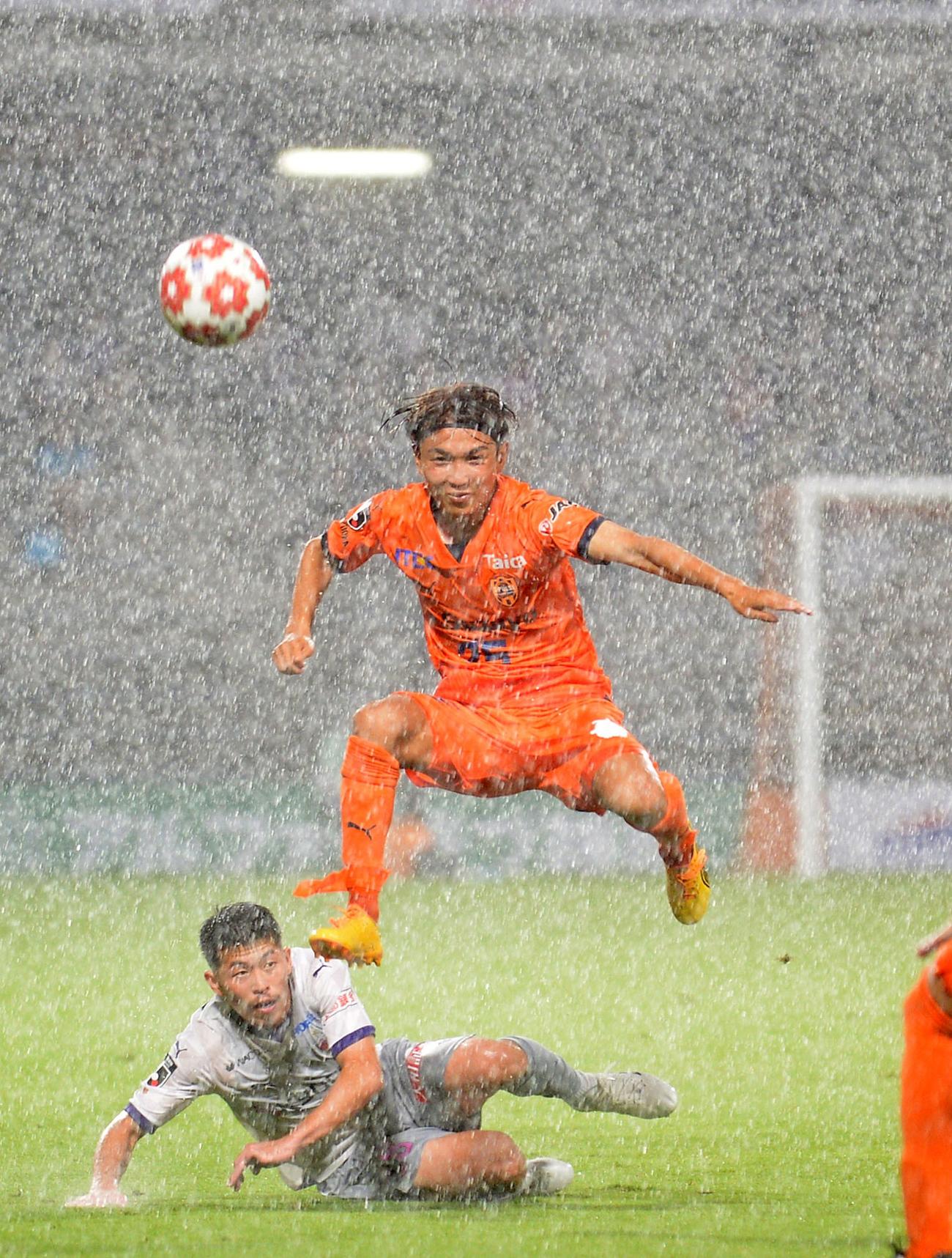 強雨の中、相手と競り合う清水成岡（右）