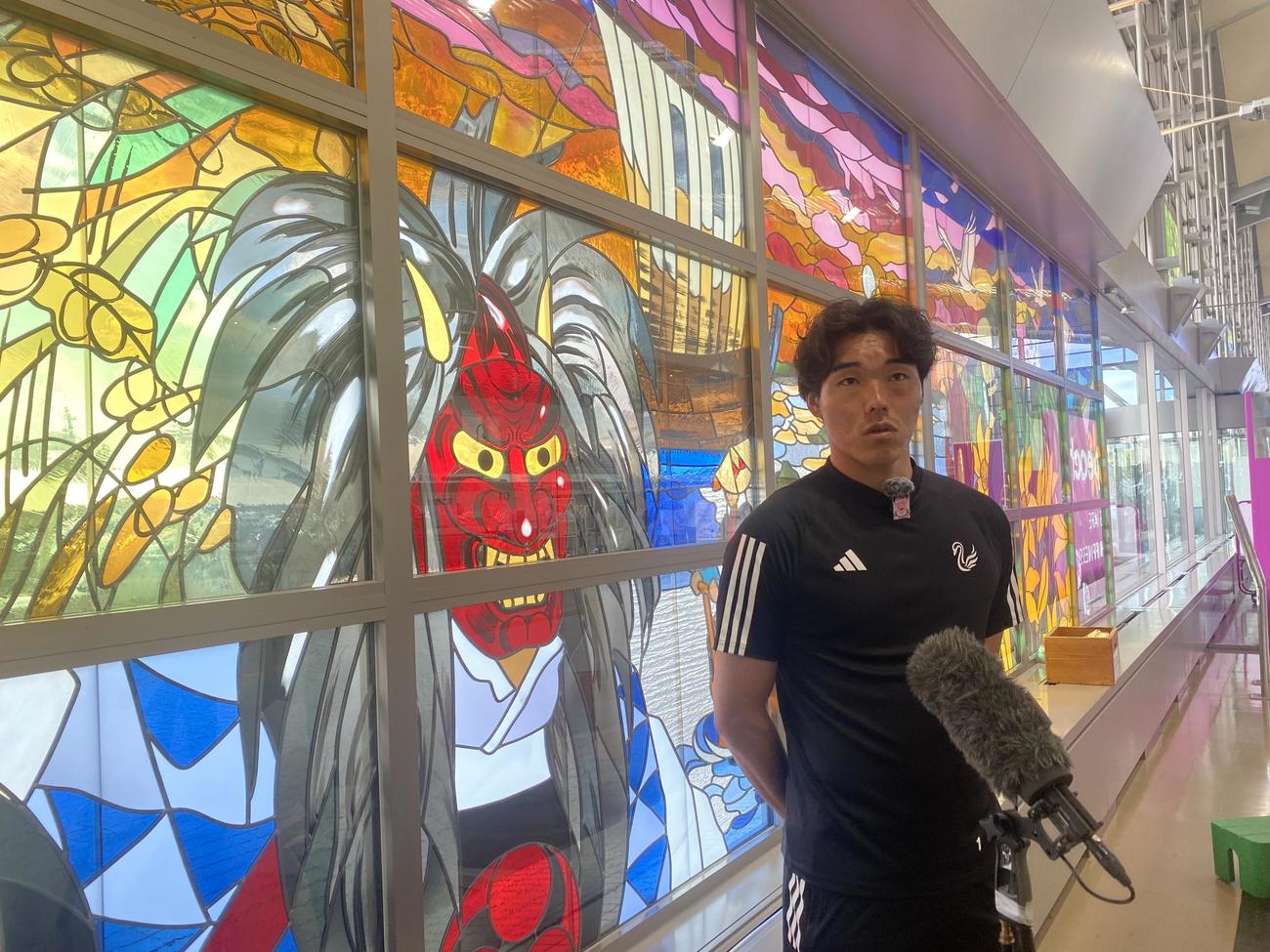 佐渡島の鬼太鼓（おんでこ）が描かれたステンドグラス前で福岡戦前日会見に参加する新潟・小島