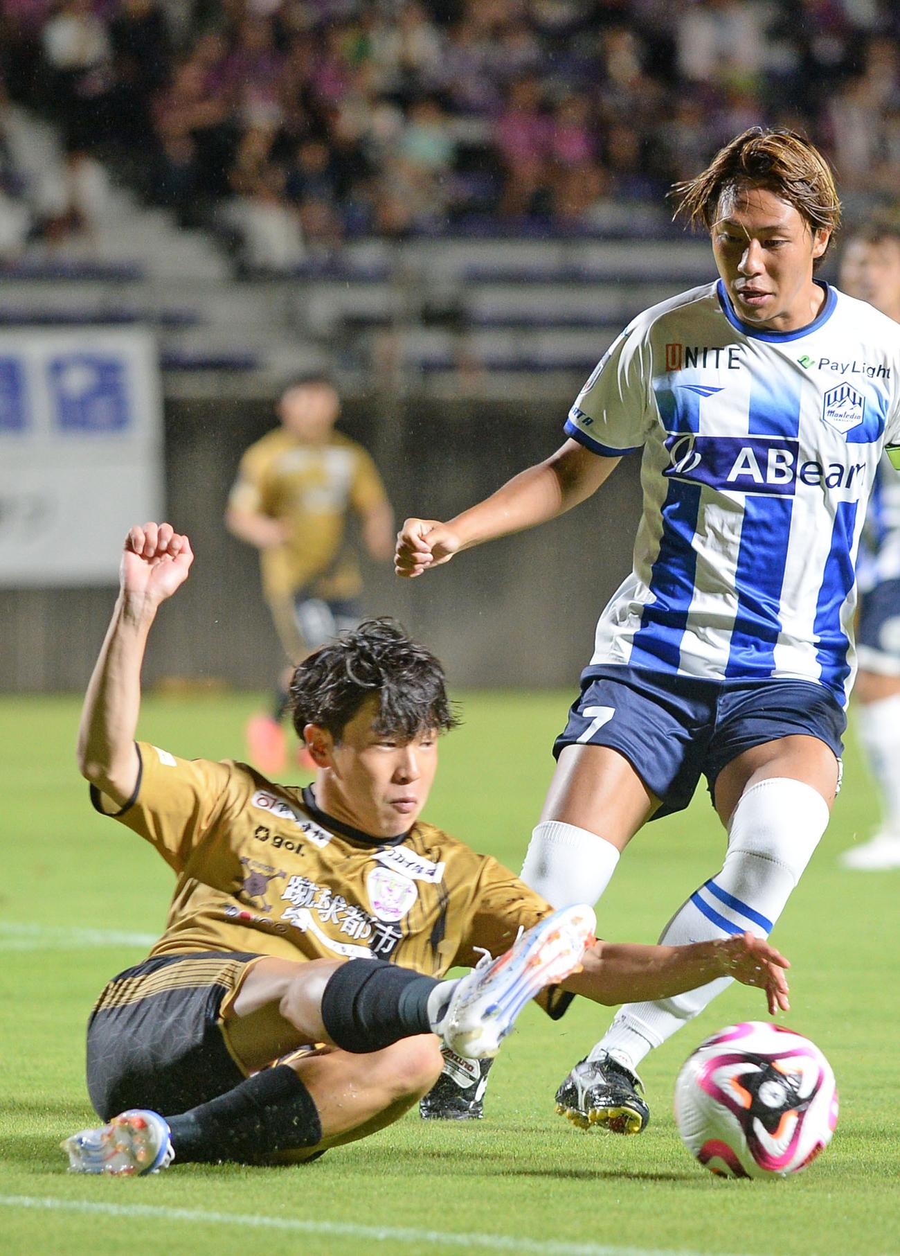 スライディングでパスをつなぐ藤枝矢村（左）