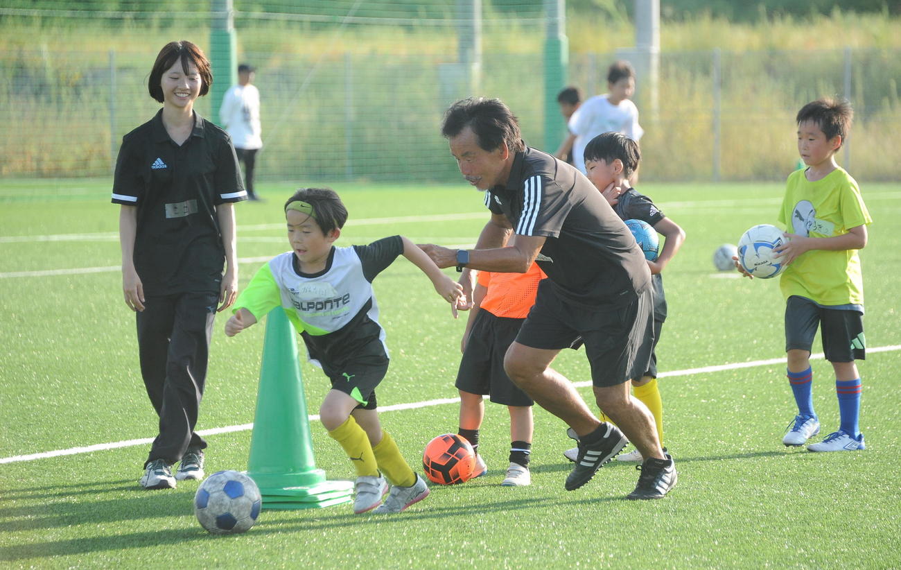 参加者とボールを追う新潟医療福祉大サッカー部の佐熊監督（右）（撮影・小林忠）