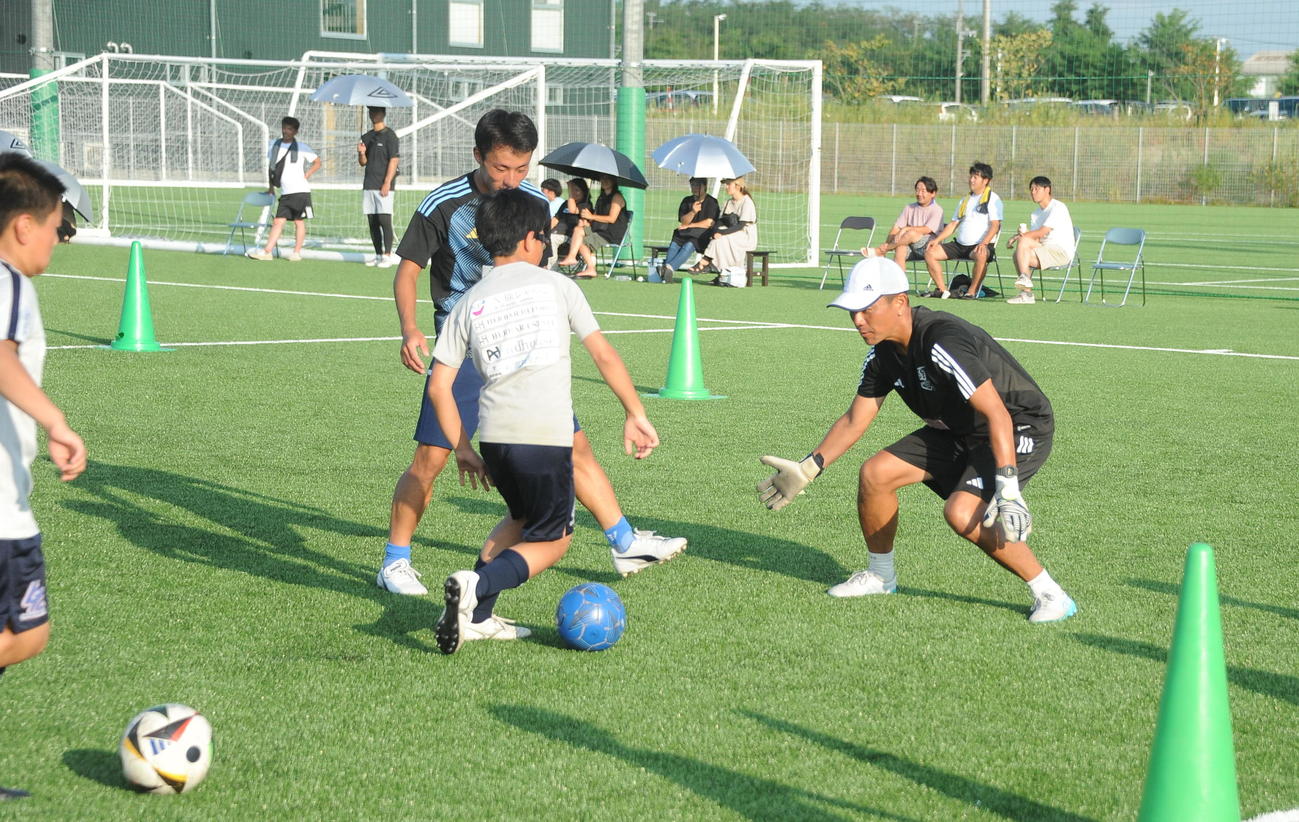 新潟医療福祉大サッカー部の佐々木GKコーチにドリブルを仕掛ける参加者（撮影・小林忠）