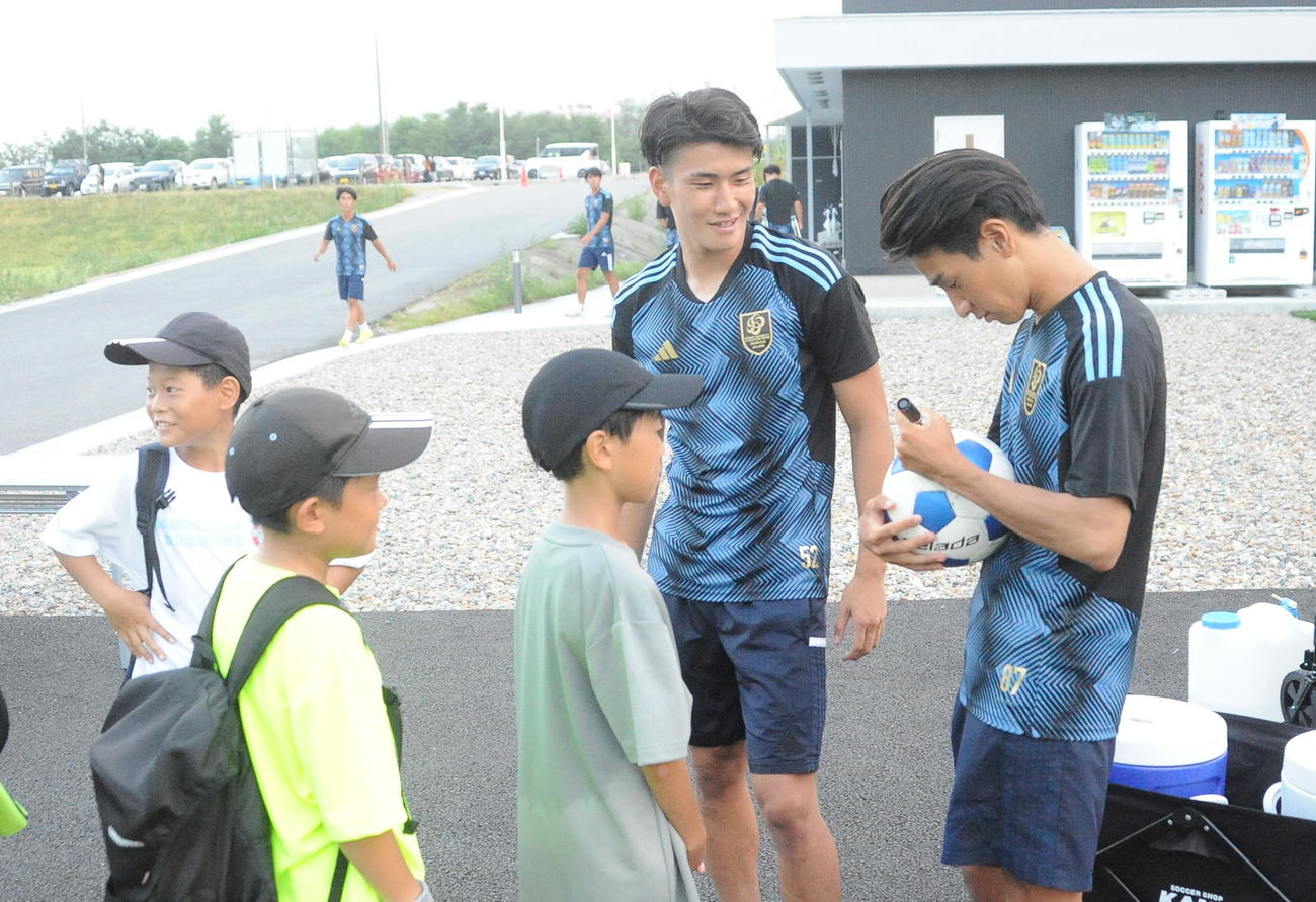 サッカースクール終了後、J2長崎加入内定の松本（右）とJ2群馬加入内定の秋元にサインをもらう小学生（撮影・小林忠）