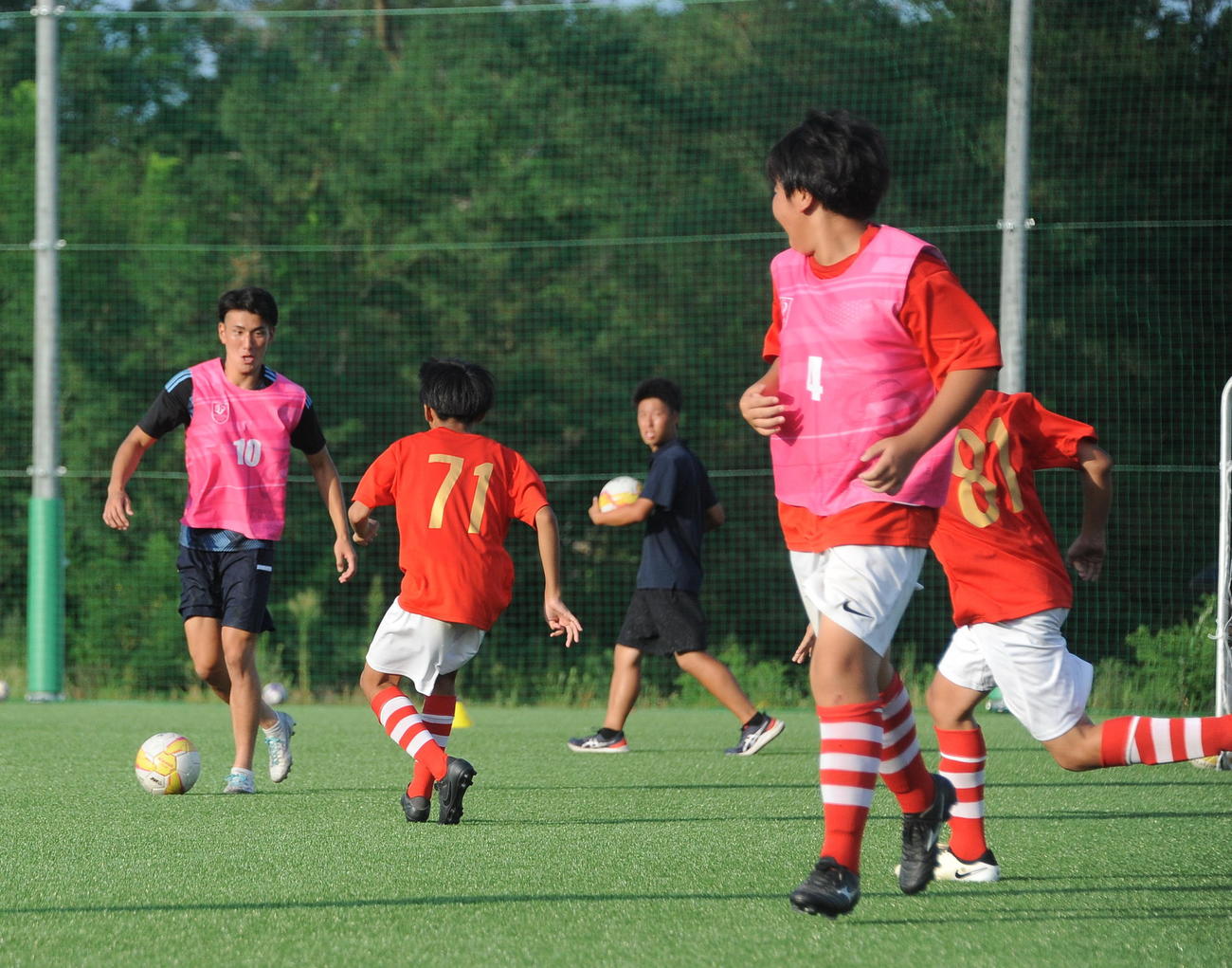 24日に新潟医療福祉大サッカー部が開催したサッカースクールで子どもたちとボールを追う秋元（左）