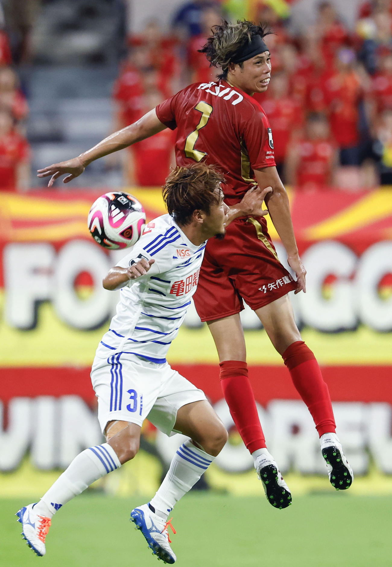 前半、競り合う名古屋・野上（上）と新潟堀米（共同）
