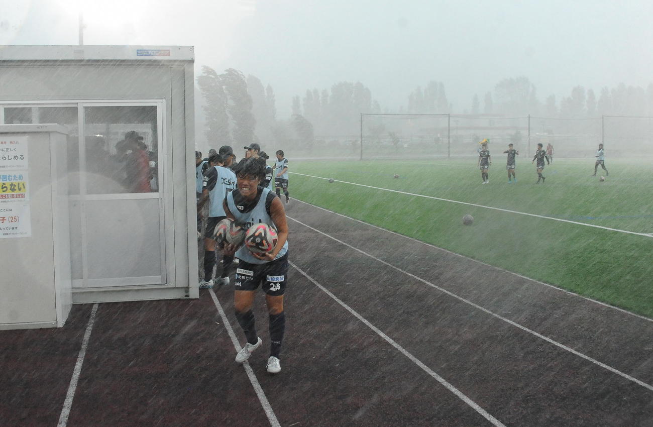 C大阪ヤンマー戦前日練習中、突然の大雨にあいクラブハウスに引き揚げる新潟Lの選手たち（撮影・小林忠）