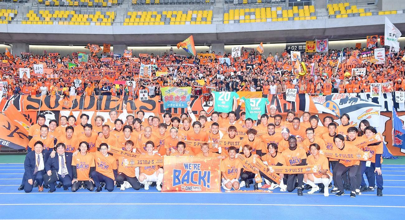 J1昇格を決め、サポーターを背に記念撮影する清水の選手やスタッフら