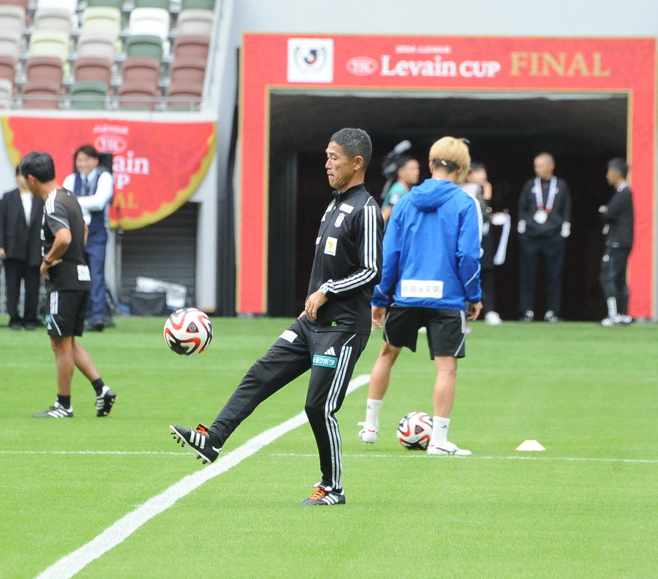 選手たちがウオーミングアップする脇で普段通りリフティングする新潟松橋監督（中央）（撮影・小林忠）