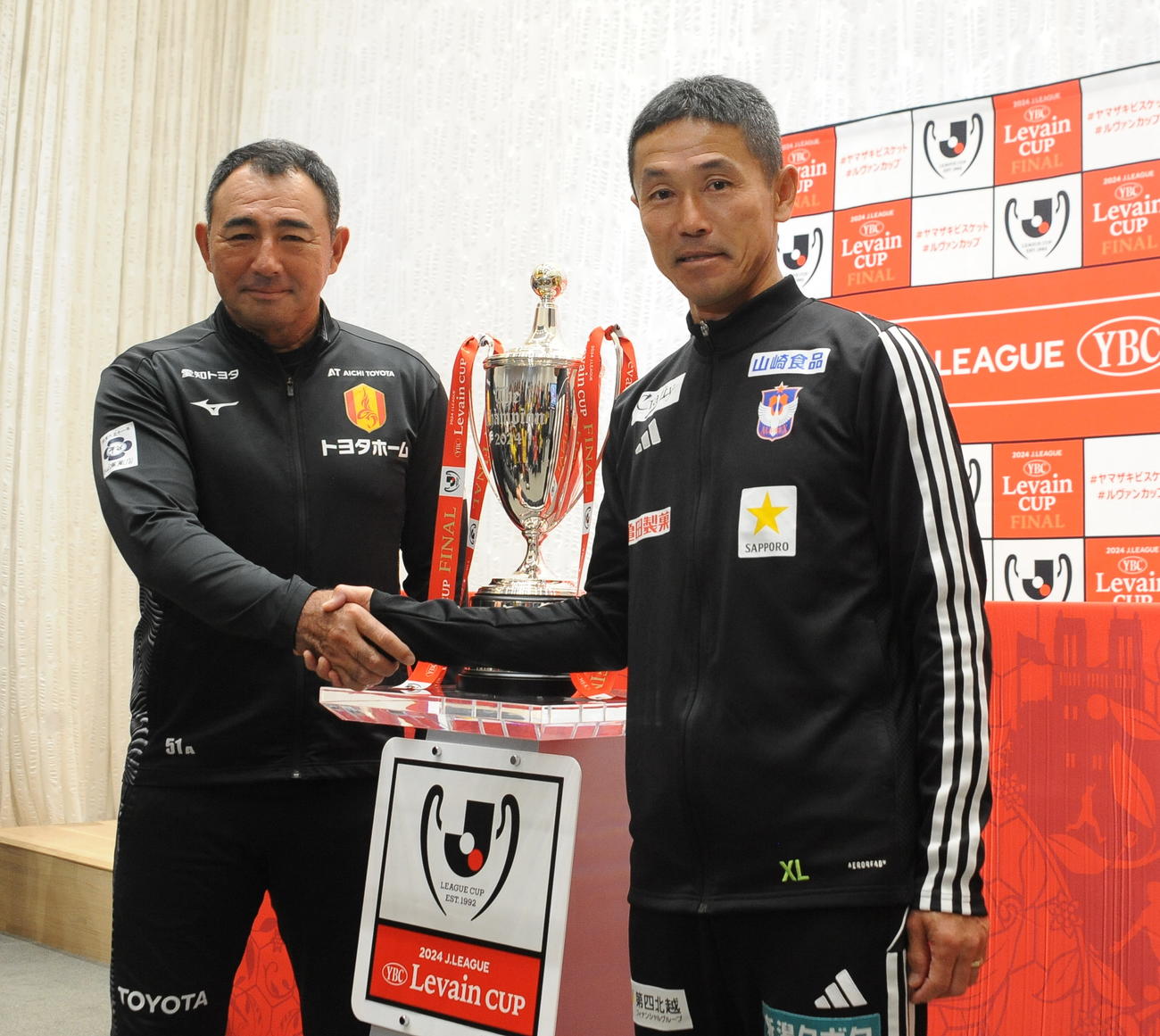 ルヴァン杯決勝に向けた合同記者会見で握手をかわす名古屋長谷川監督（左）と新潟松橋監督（撮影・小林忠）