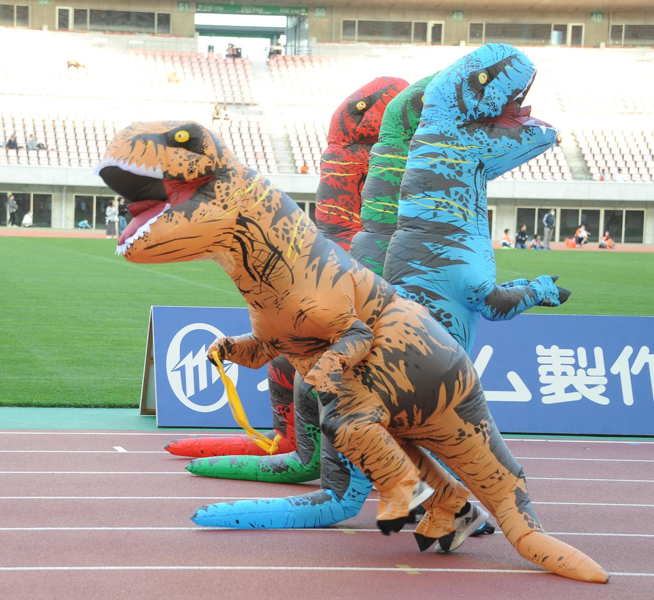 サンクスフェスタの選手チーム対抗戦で行われた障害物リレーで、恐竜の着ぐるみを着て激走する新潟太田（左）