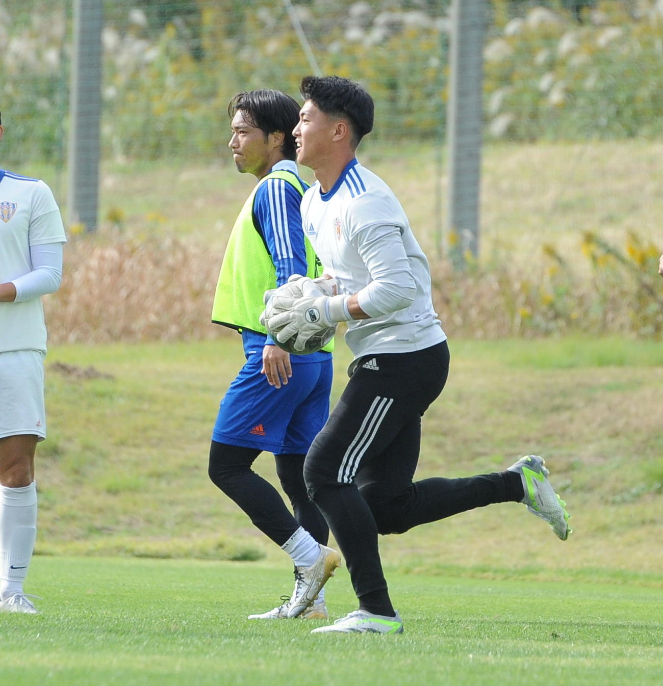 ボールをキャッチした瞬間に前進するJAPANサッカーカレッジ倉持（右）（撮影・小林忠）