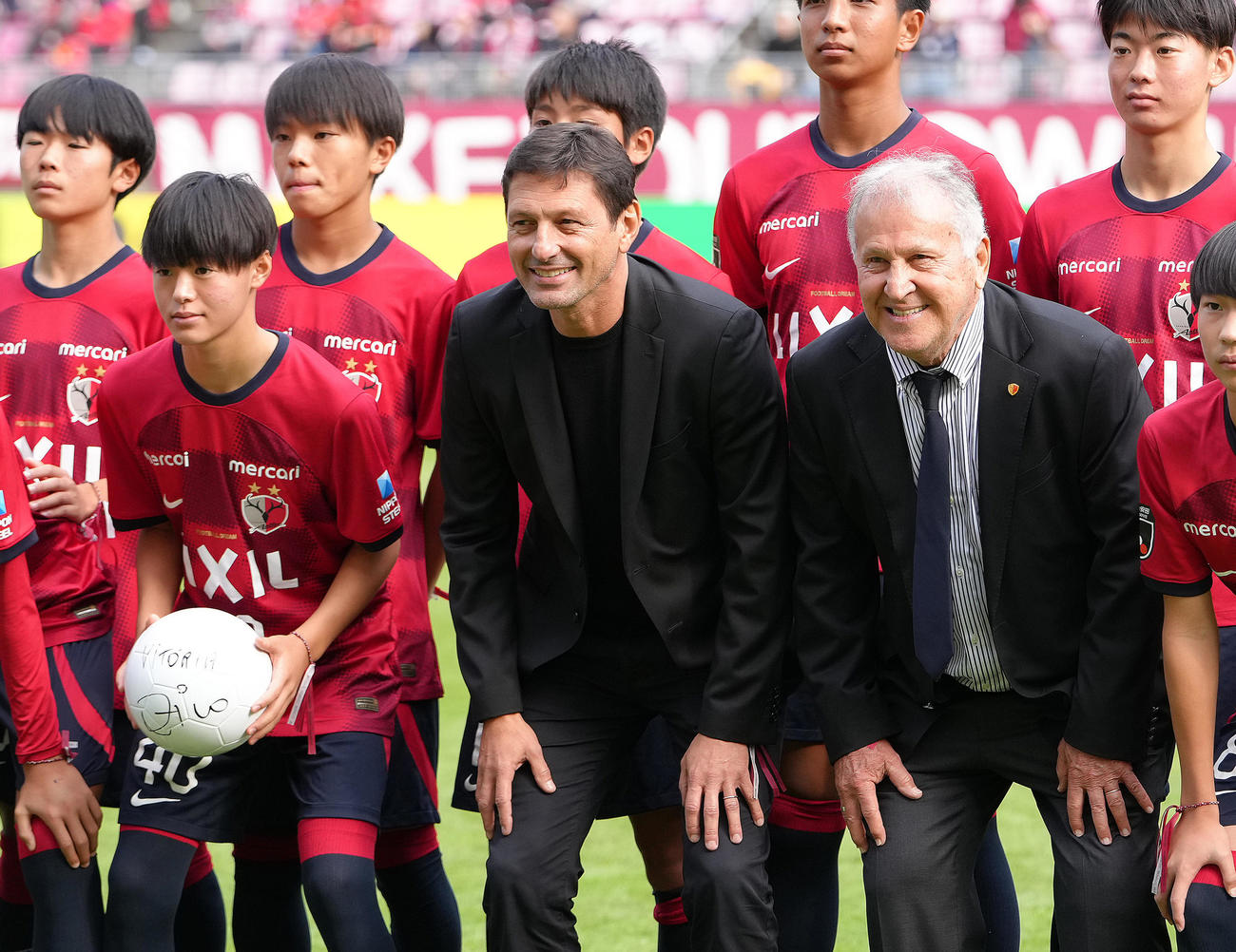 試合前、引退30周年セレモニーを行ったジーコCA（右）と笑顔で記念撮影する、左から小笠原満男氏の長男で鹿島ジュニアユースの小笠原央（ひろ）、レオナルド氏（撮影・足立雅史）