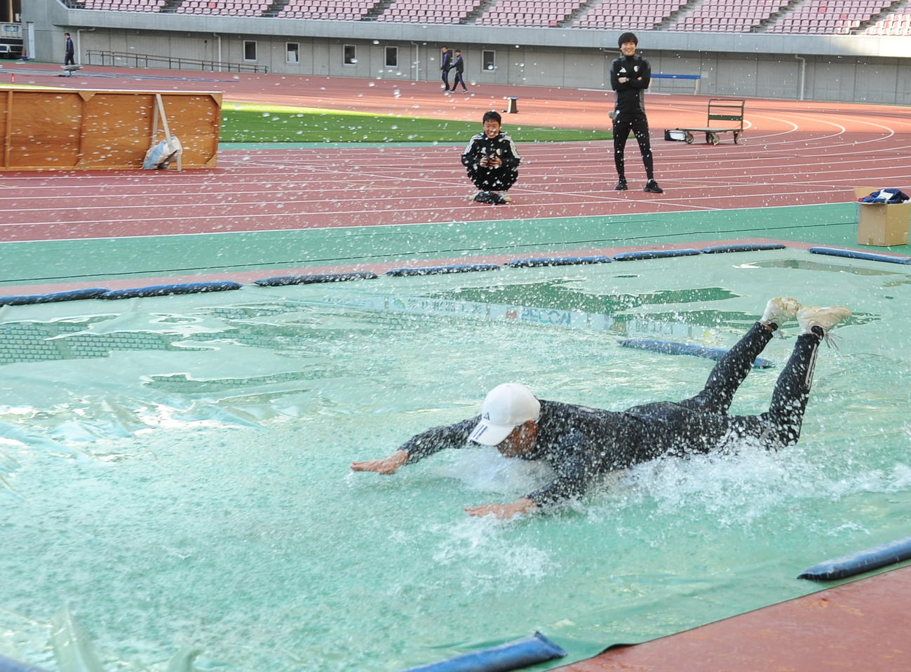 新潟明訓対開志学園JSC 9大会ぶり7度目の優勝を果たし、選手たちにあおられて水たまりにダイブする新潟明訓・坂本監督（撮影・小林忠）