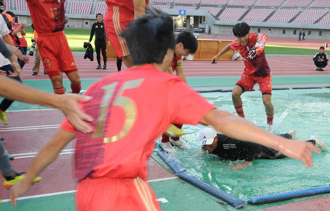 新潟明訓対開志学園JSC 9大会ぶり7度目の優勝を果たし、選手たちにあおられて水たまりにダイブする新潟明訓・坂本監督（右）（撮影・小林忠）