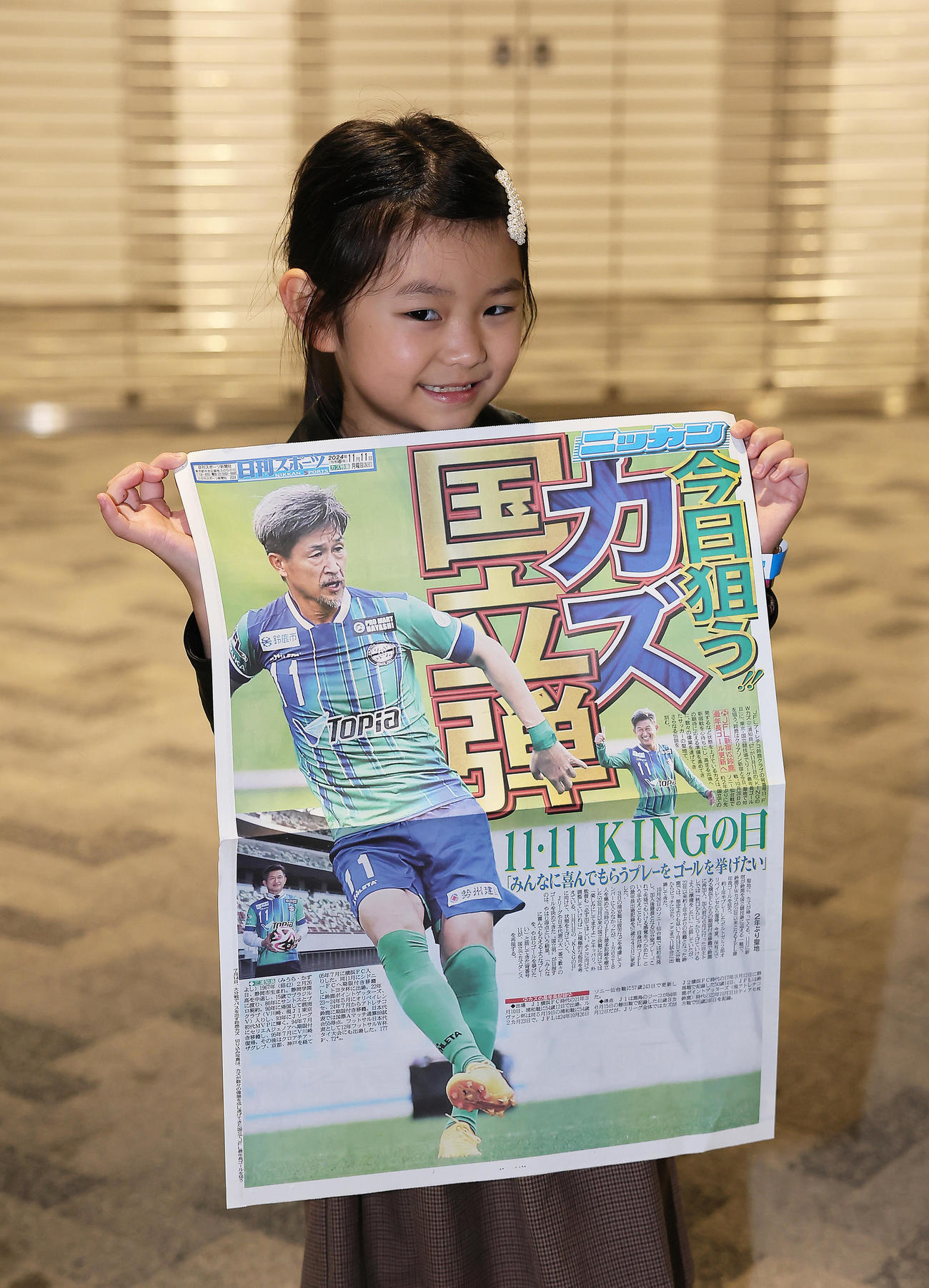 新宿対鈴鹿　試合前、本紙特別号外を手に笑顔を見せる子ども（撮影・足立雅史）