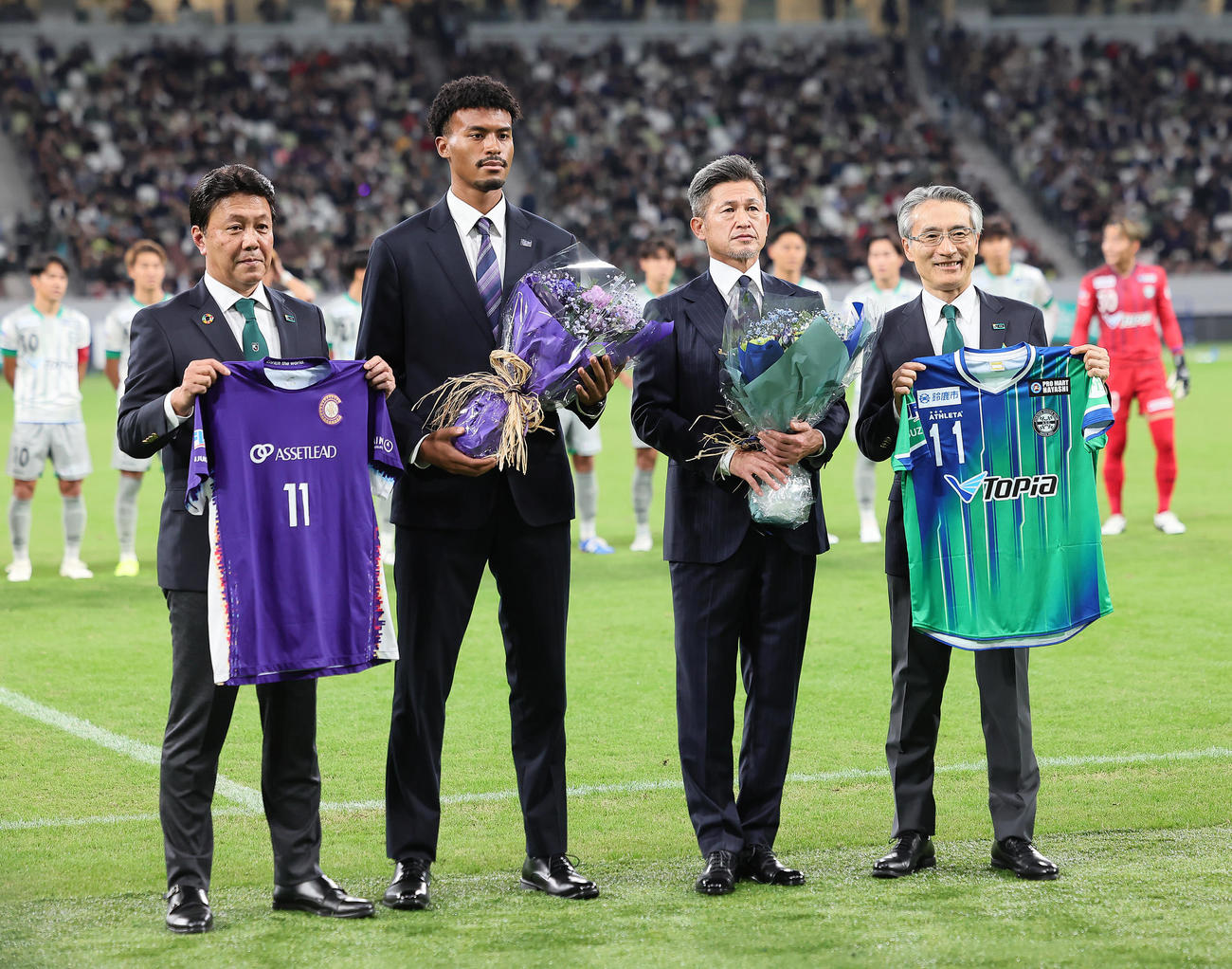 試合前のセレモニーで明治安田生命保険相互会社永島英器取締役代表執行役社長（右端）から花束を受け取り記念撮影する鈴鹿カズ（中央右）（撮影・足立雅史）