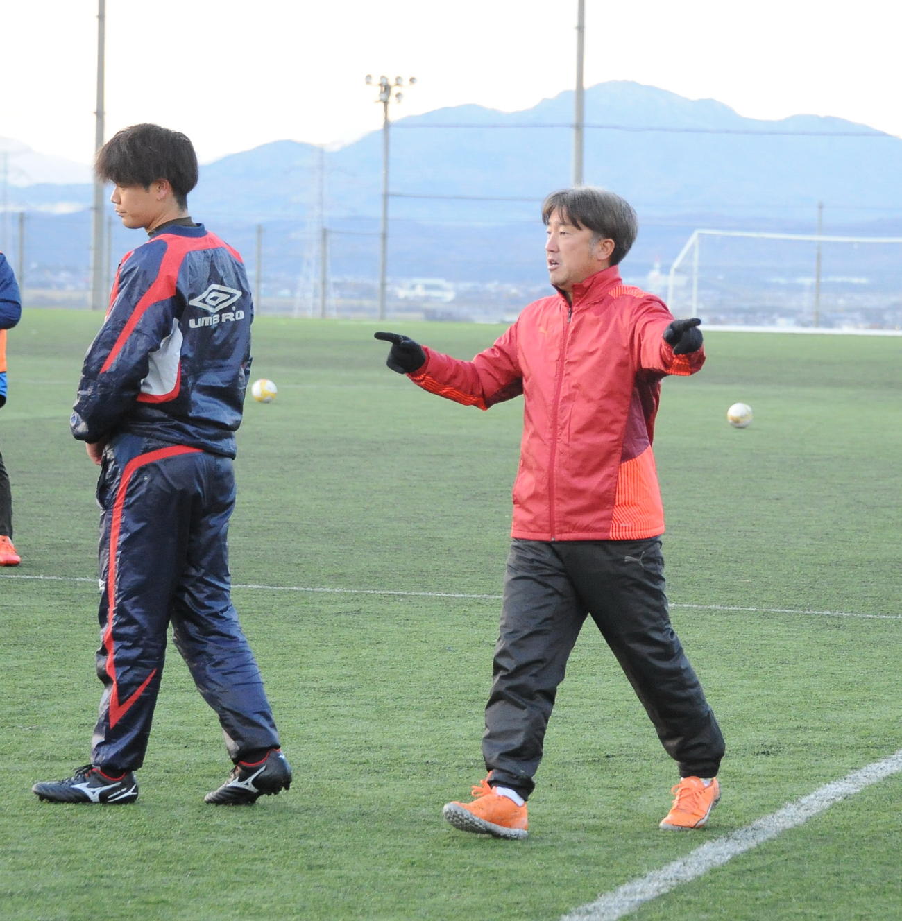 パスワークの練習で選手にアイデアを伝える新潟産大・岡村監督（右）（撮影・小林忠）