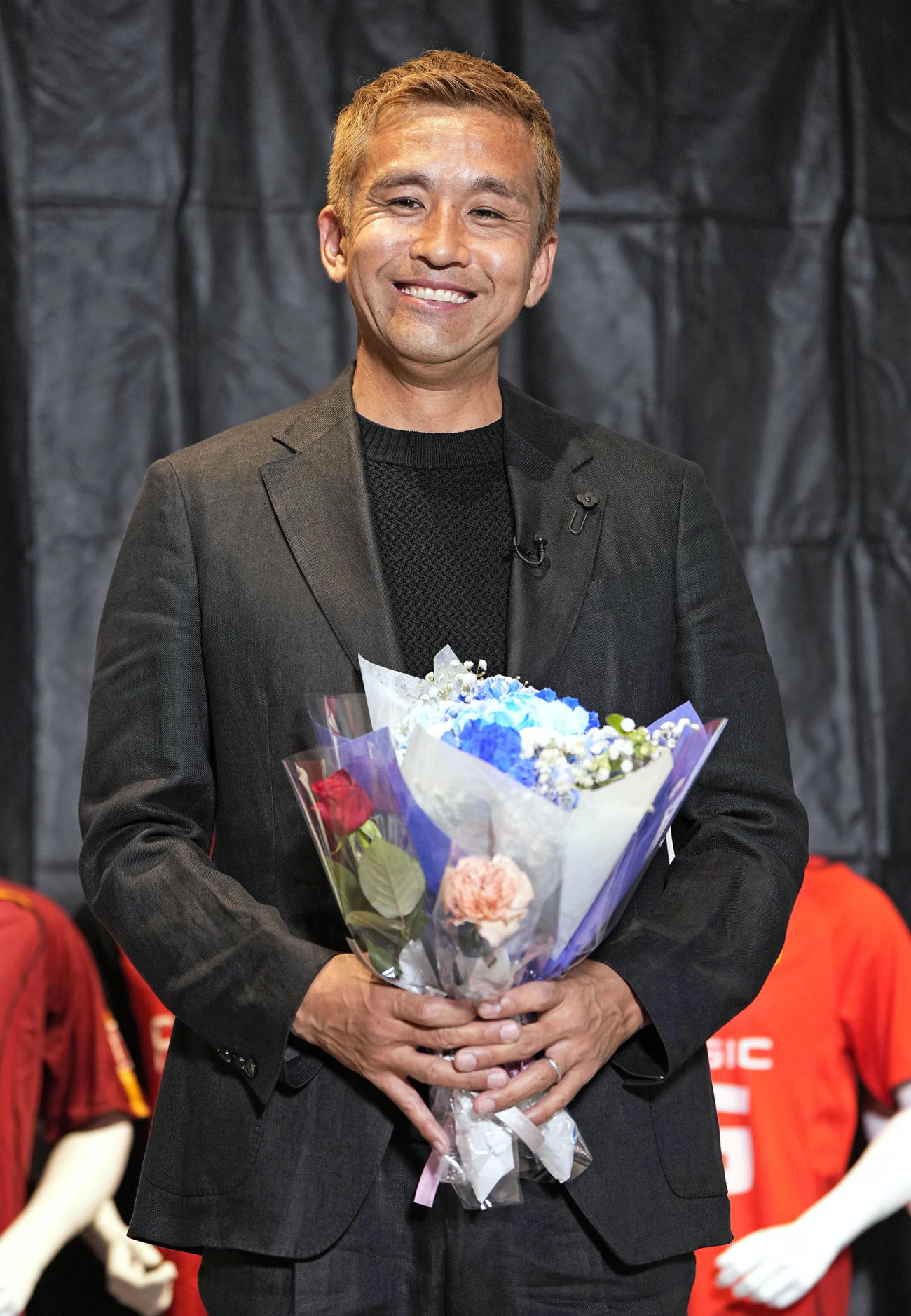 引退記者会見で、花束を手に笑顔を見せる南葛SCの稲本潤一（共同）