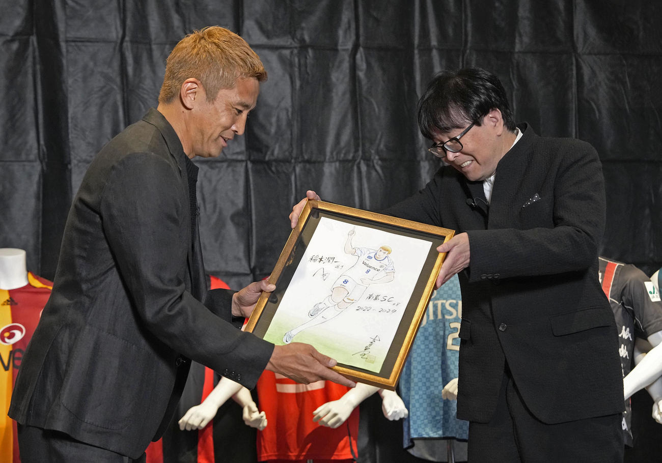 引退記者会見で高橋陽一氏からイラストを贈られる南葛SCの稲本潤一（共同）