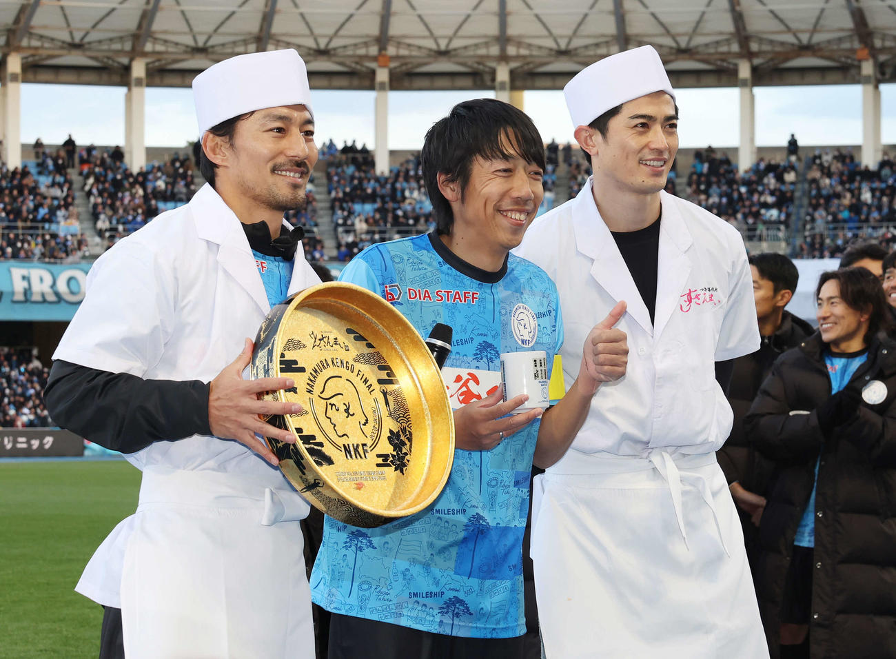 中村憲剛引退試合　試合後、すし屋の格好をした家長昭博（左）と谷口彰悟（右）と笑顔で記念撮影する中村憲剛（撮影・宮地輝）