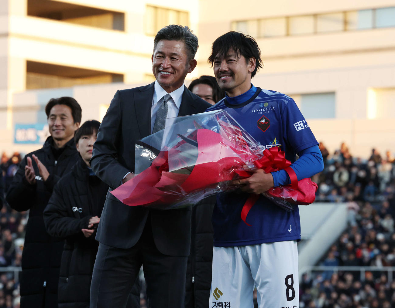 松井大輔引退試合　MATSUI FRIENDS対JAPAN DREAMS　試合後、三浦知良（左）から花束を受け取った松井大輔（撮影・宮地輝）