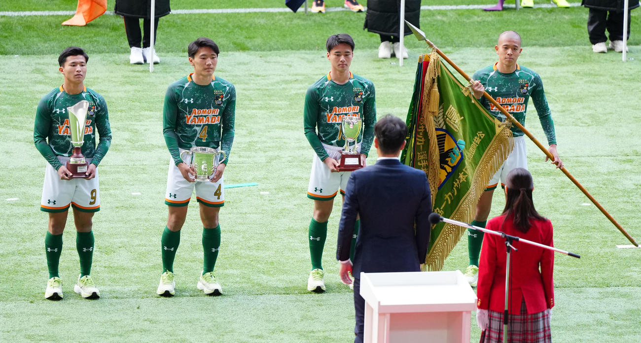 全国高校サッカー選手権の開会式で優勝旗などを返還する小沼（右端）ら青森山田の選手たち（撮影・江口和貴）
