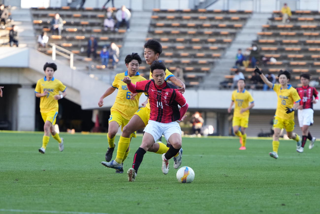 西目対日章学園　前半、ドリブルする日章学園・高岡（中央）