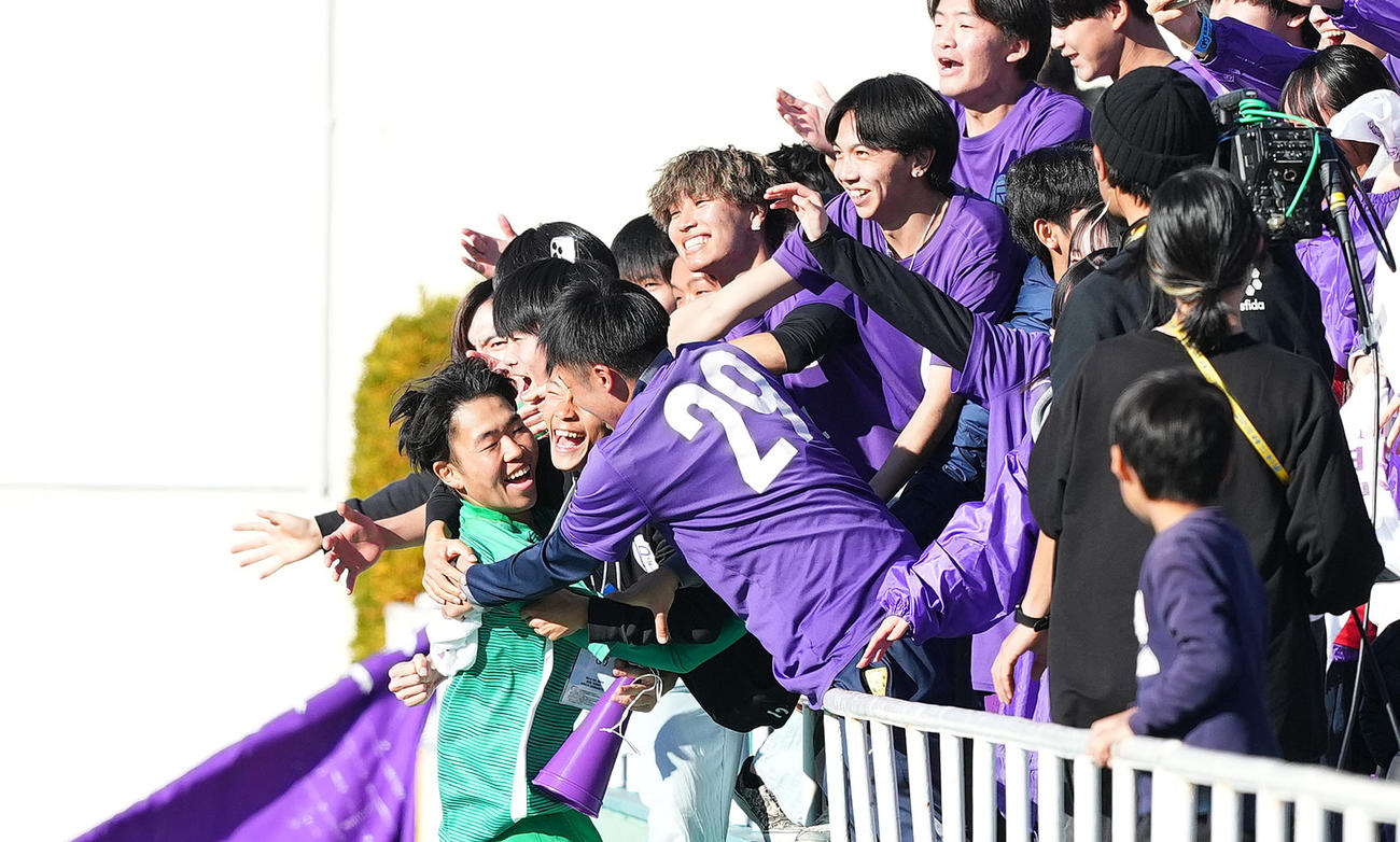 龍谷富山対那覇西　PKで那覇西を破り、スタンドの仲間と抱き合う龍谷富山GK吉田（左端）（撮影・菅敏）