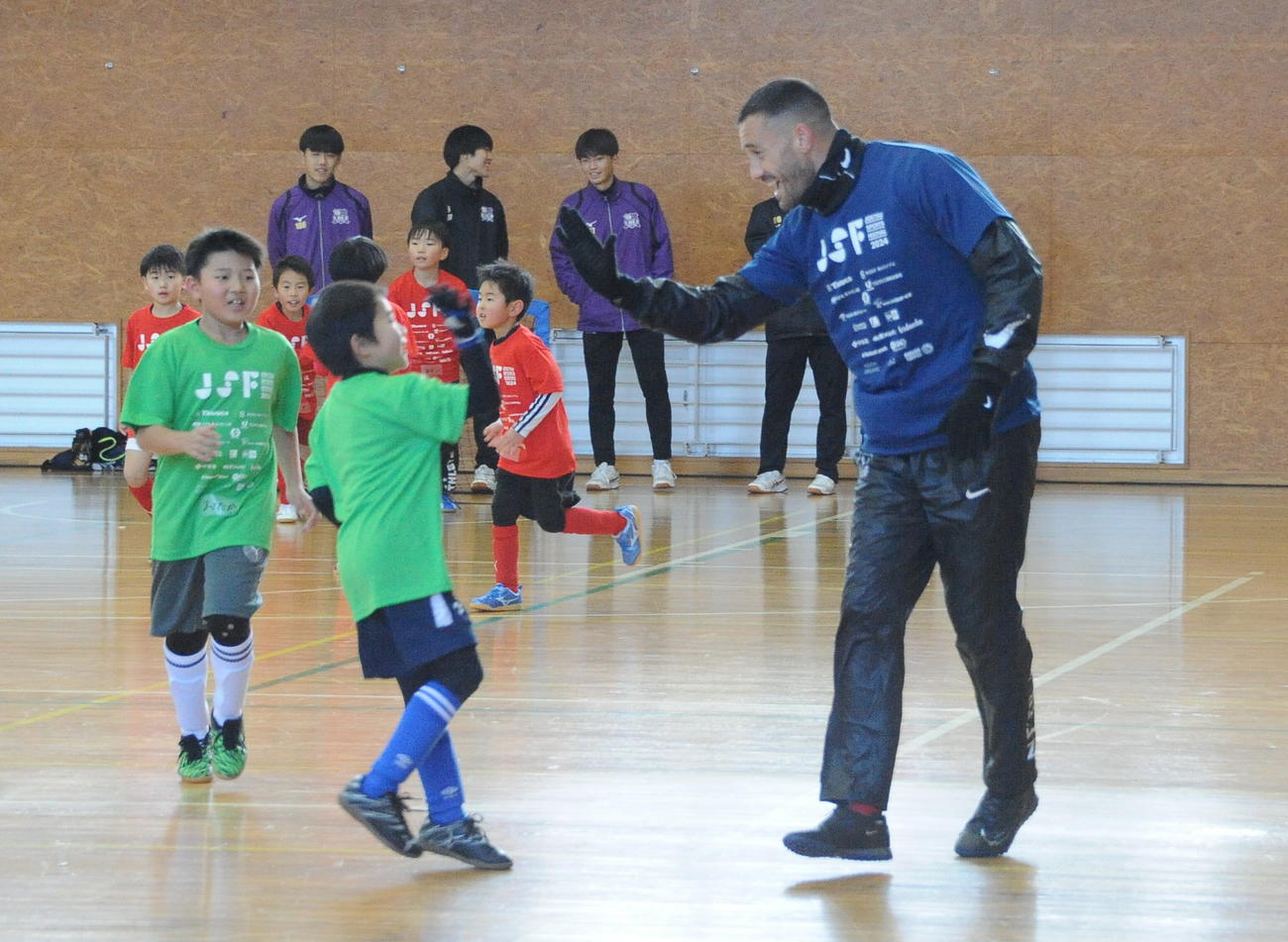 昨年12月に行われたサッカー教室で子どもたちとタッチする舞行龍ジェームズ（右）（撮影・小林忠）
