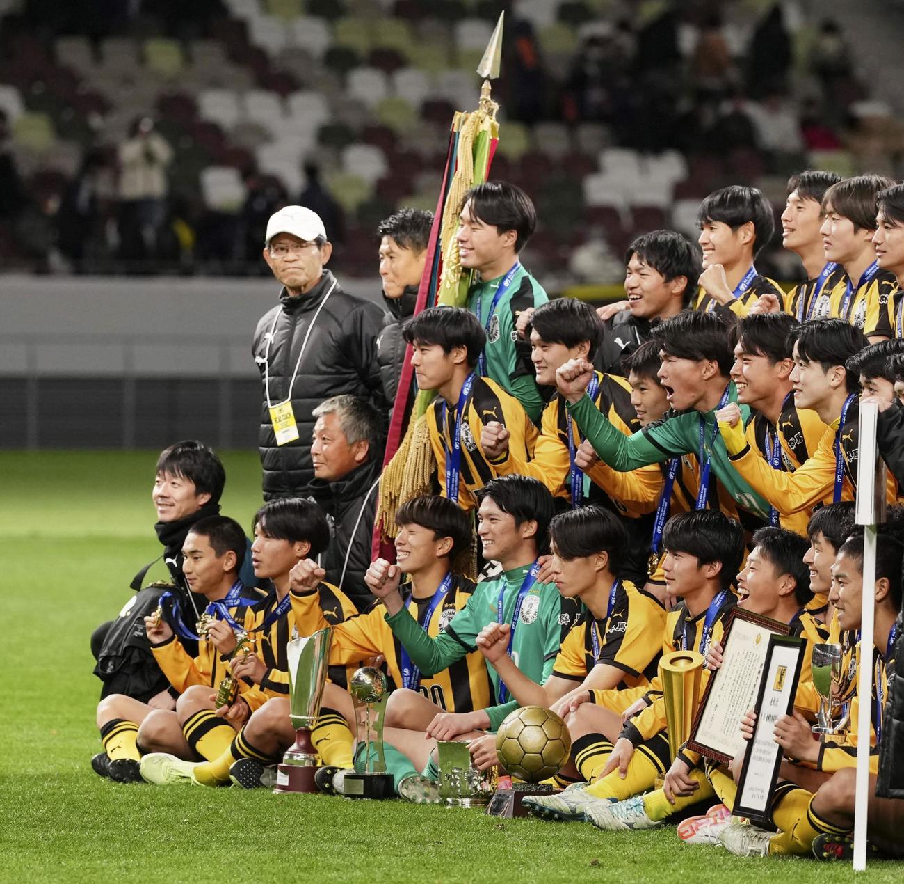 優勝を果たし、写真に納まる選手たちを見つめる前橋育英・山田監督（後列左端）＝国立競技場（共同）