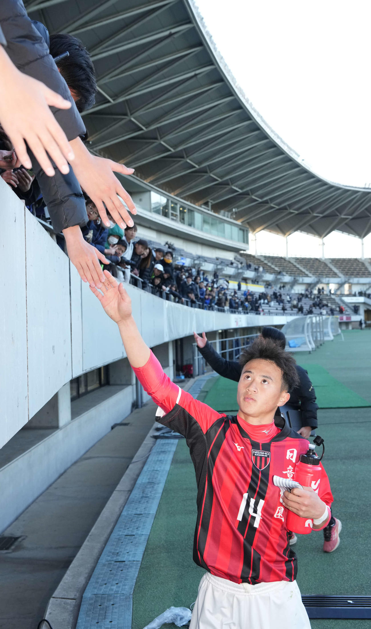 スタンドのファンとハイタッチする日章学園・高岡（2024年12月29日撮影）