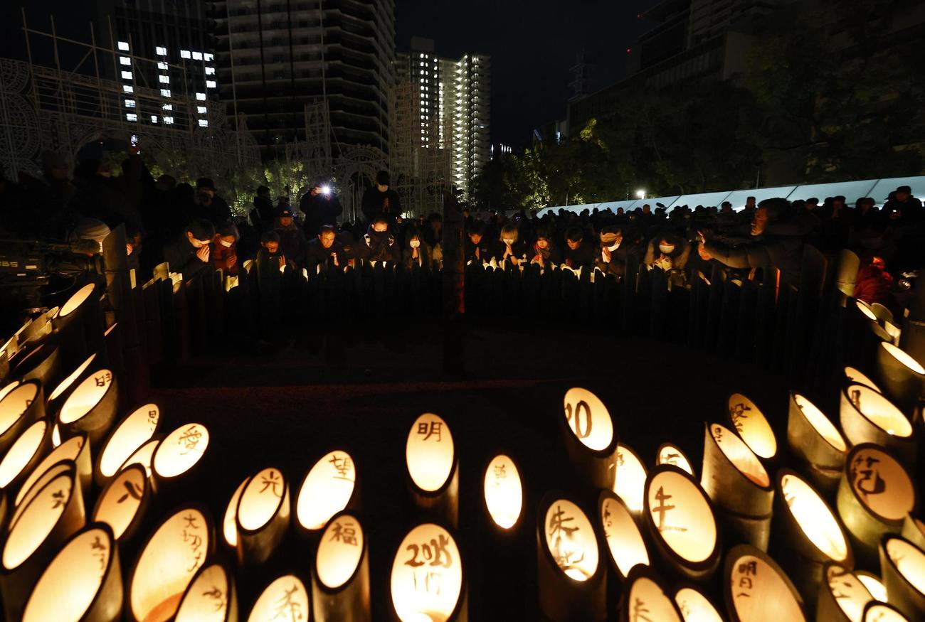 阪神大震災から30年となり、発生時刻に合わせて黙とうする人たち＝17日午前5時46分、神戸市中央区の東遊園地（共同）