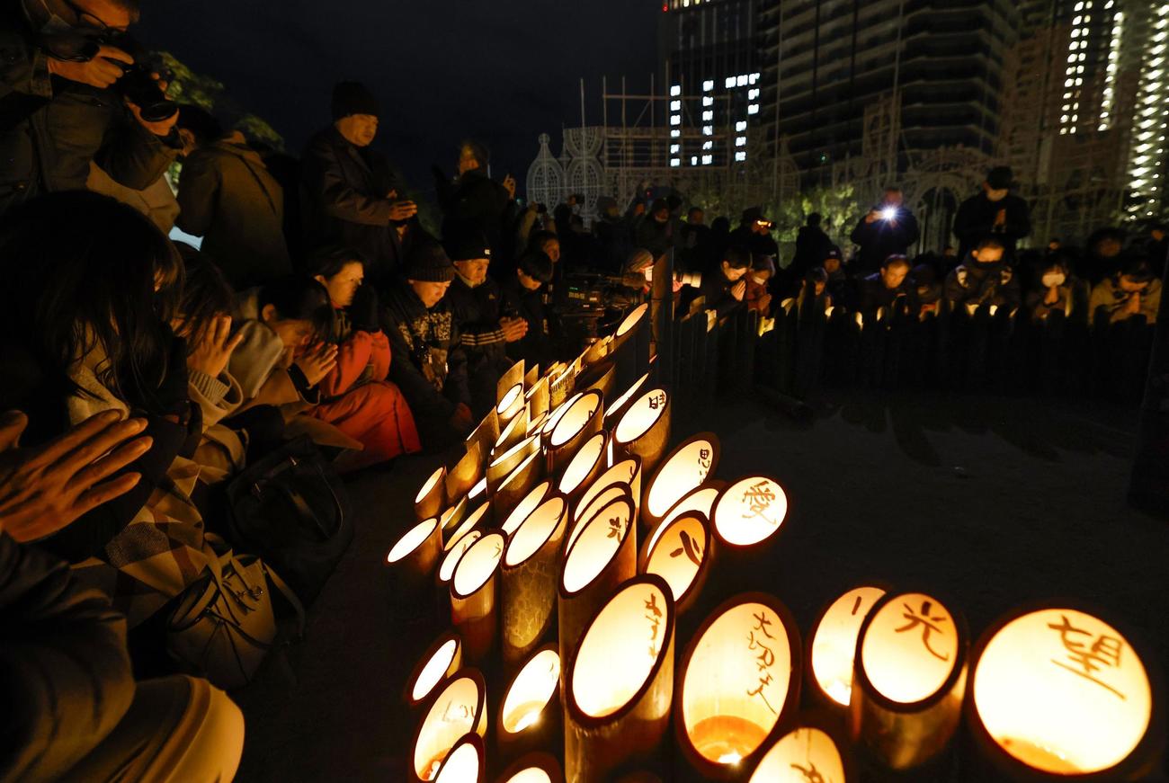 阪神大震災から30年となり、追悼会場で黙とうする人たち＝17日早朝、神戸市中央区の東遊園地（共同）