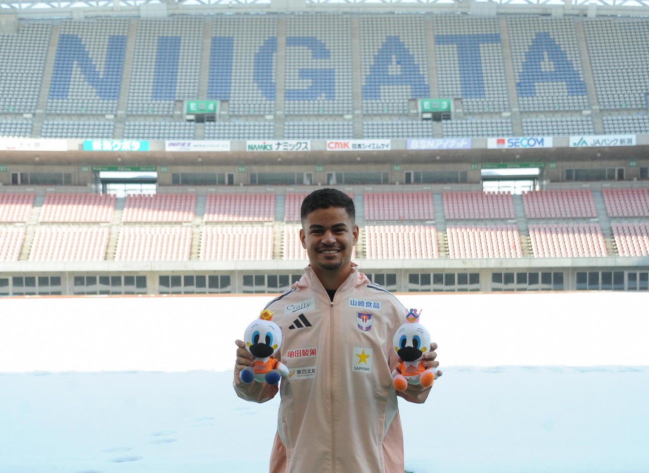雪が残るホームスタジアムを背に新潟での活躍を誓う新加入ミゲル（撮影・小林忠）