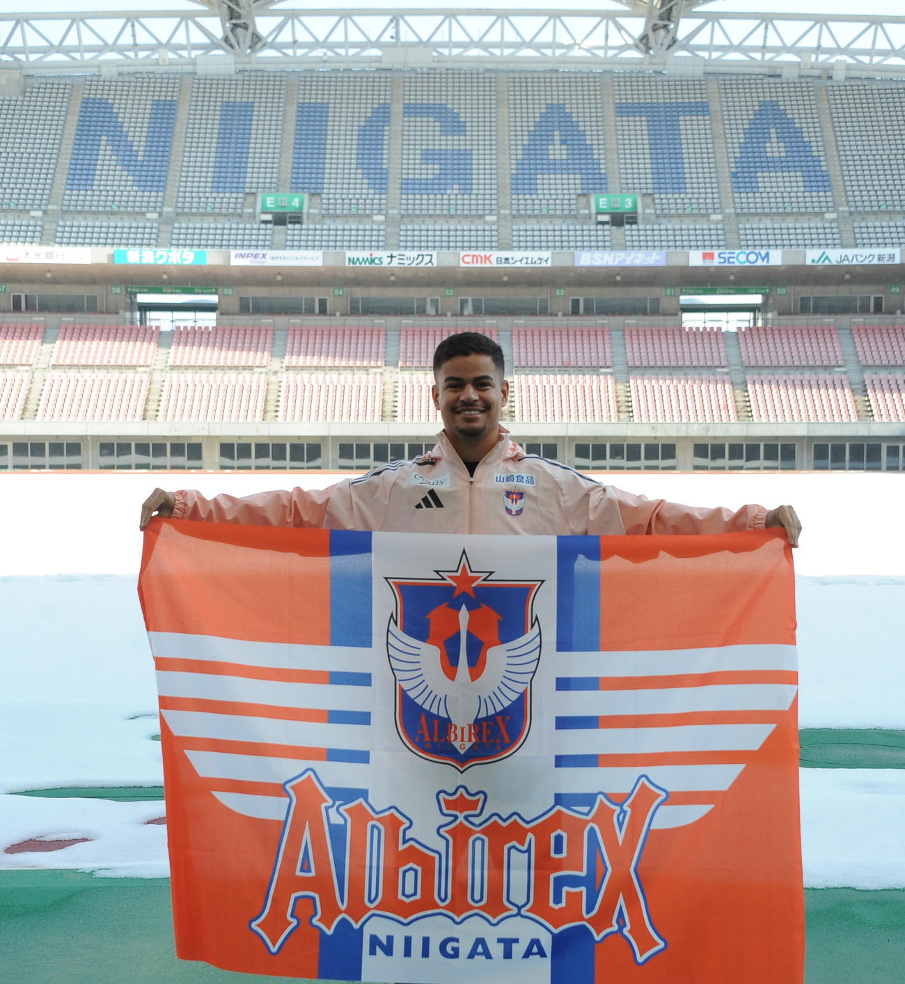 雪が残るホームスタジアムを背に新潟での活躍を誓う新加入ミゲル（撮影・小林忠）