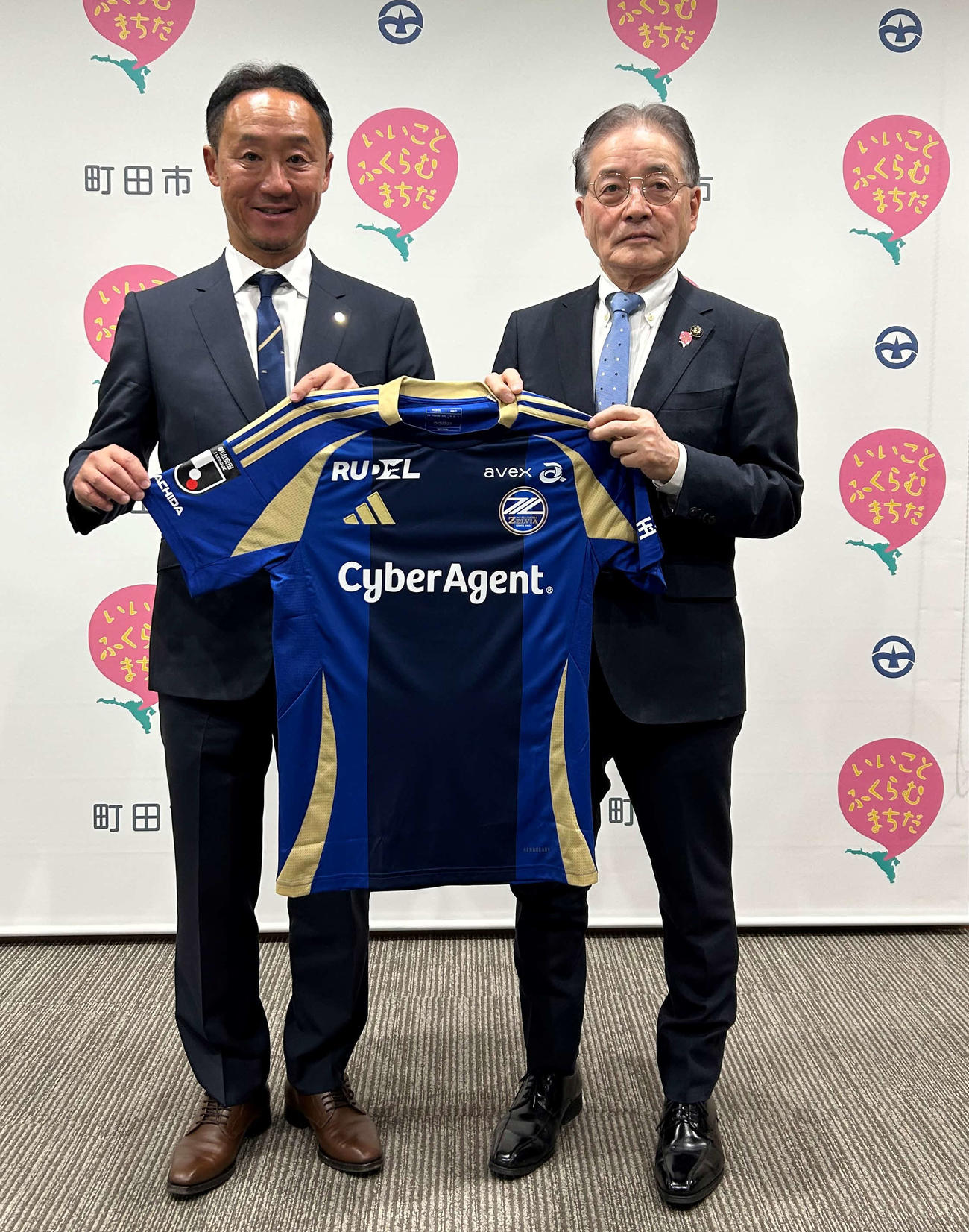 町田市役所を表敬訪問した黒田剛監督（左）は石阪丈一市長にユニホームを手渡し、記念撮影に収まる