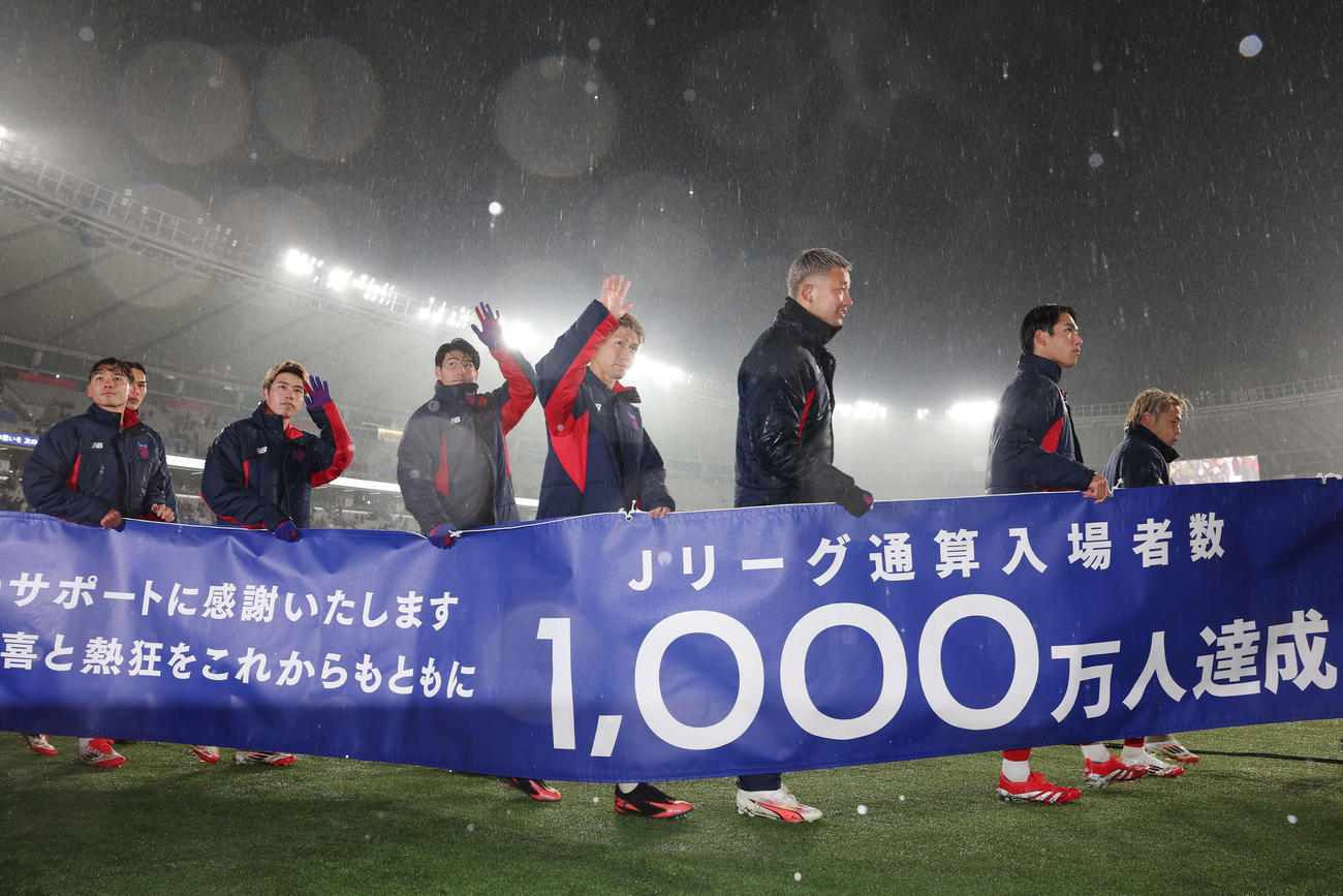 東京対湘南　試合後、Jリーグ通算入場者数、1000万人達成のバナーを手にスタジアムを回る東京橋本（中央）ら選手たち（撮影・宮地輝）