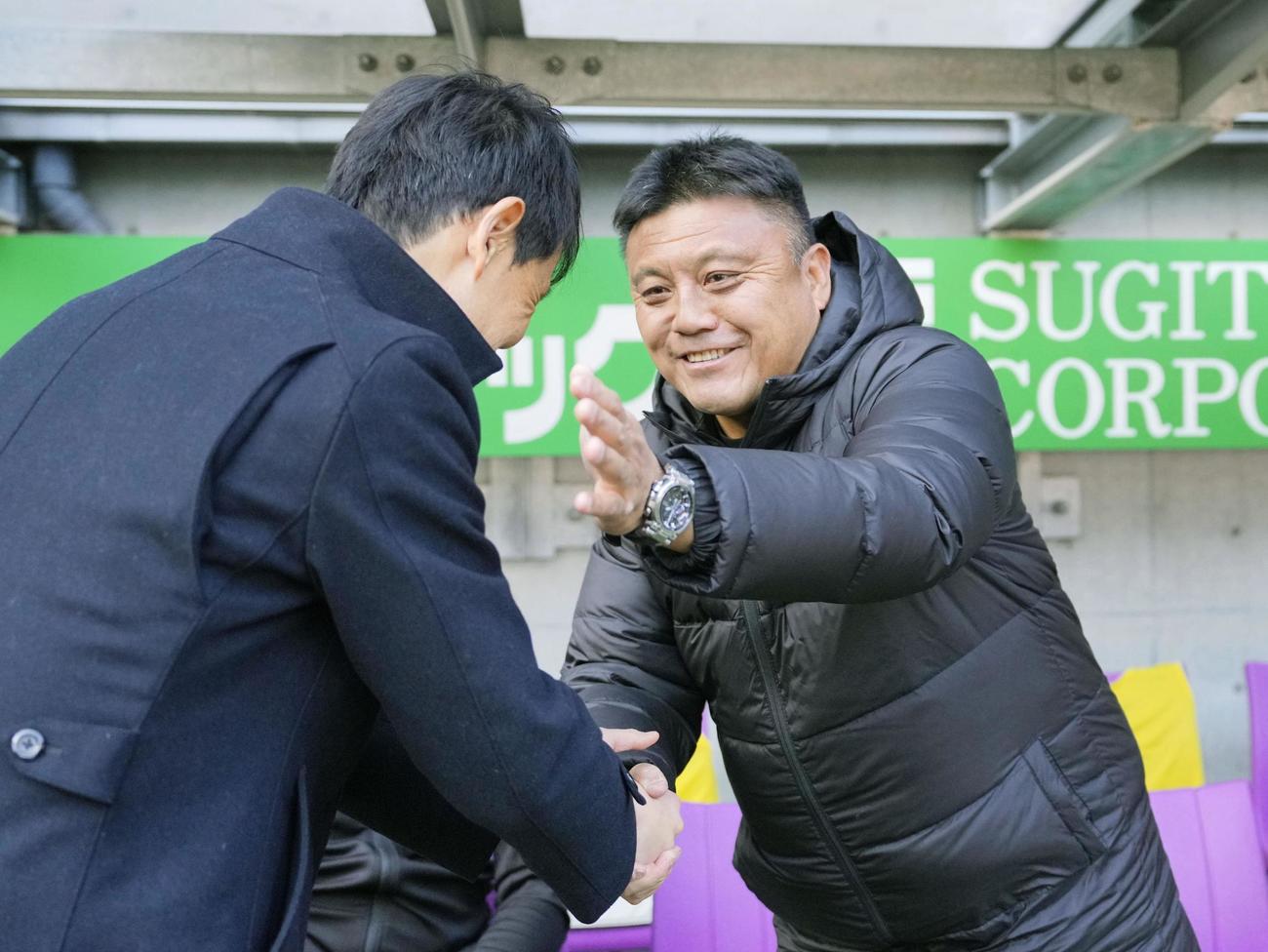 試合前、福岡・金明輝監督（左）と握手する京都・曺貴裁監督（共同）