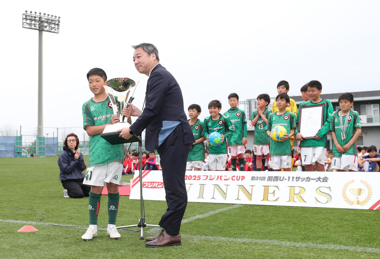 フジパンCUPの優勝トロフィーをフジパン株式会社枚方工場長川坂昌史氏（右）から授与される京都長岡京SS近原俊葵（撮影・白石智彦）