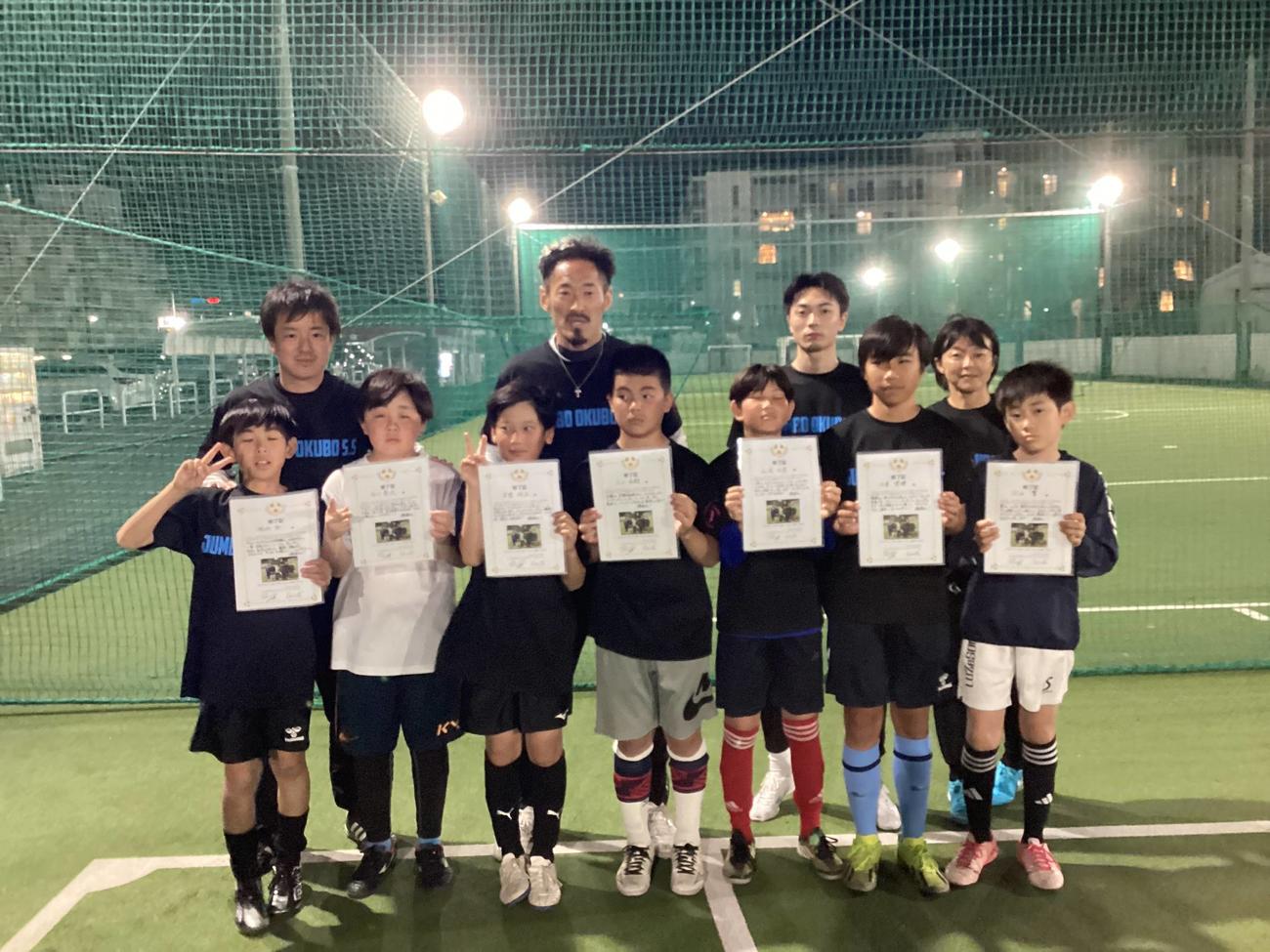 ジャンボ大久保ストライカースクールの1期生で卒業する6年生に賞状を渡したFIFTY CLUBのFW大久保哲哉（後列左から2人目）