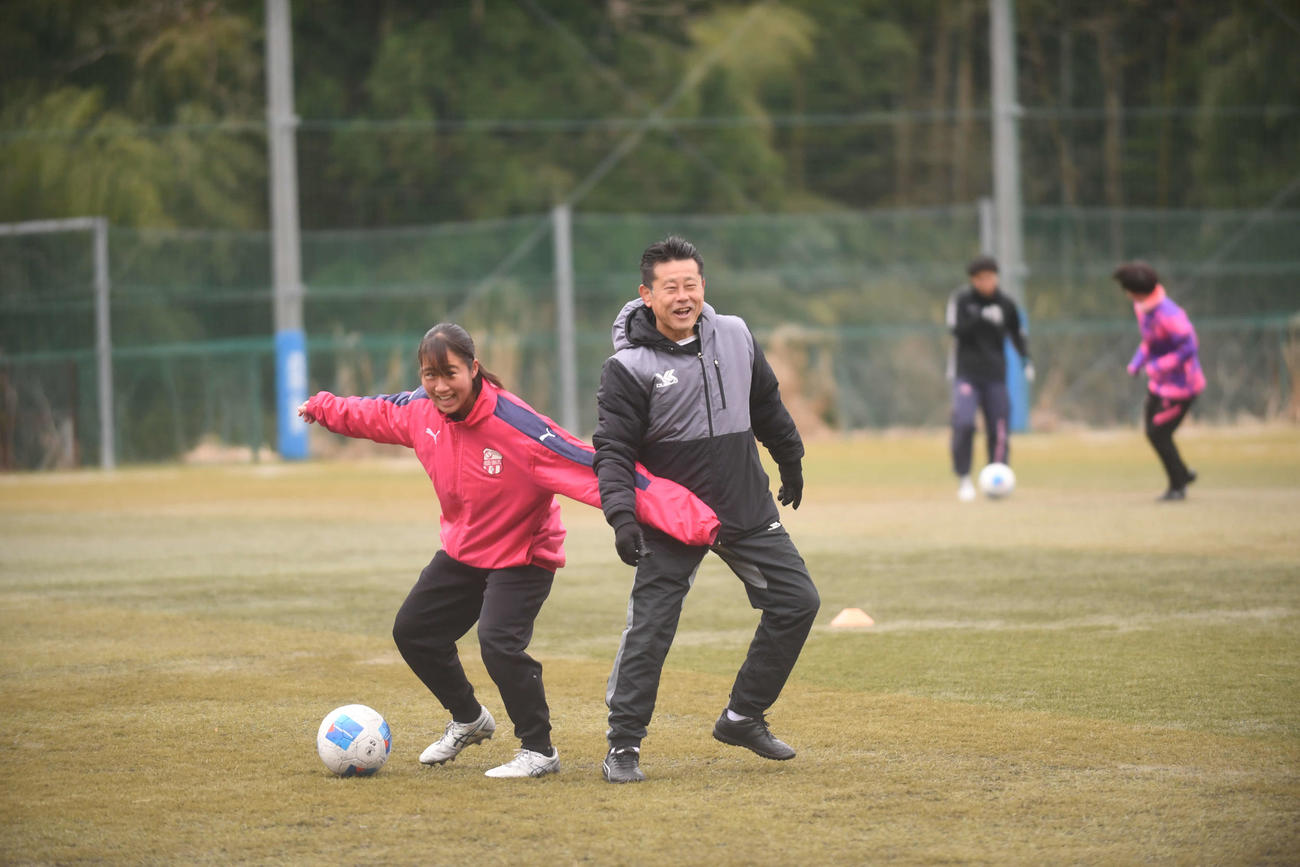 選手と笑顔でボールを奪い合う鈴木監督