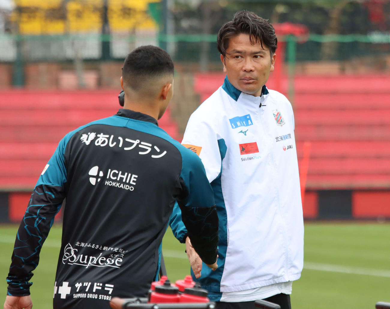 練習前に札幌青木（左）とあいさつする岩政監督（撮影・保坂果那）