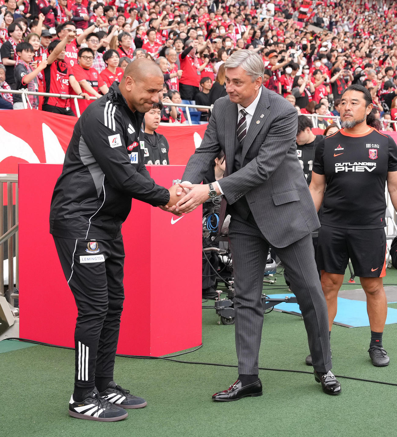 浦和対横浜　試合前、握手を交わす横浜キスノーボHC（左）と浦和スコルジャ監督（撮影・足立雅史）