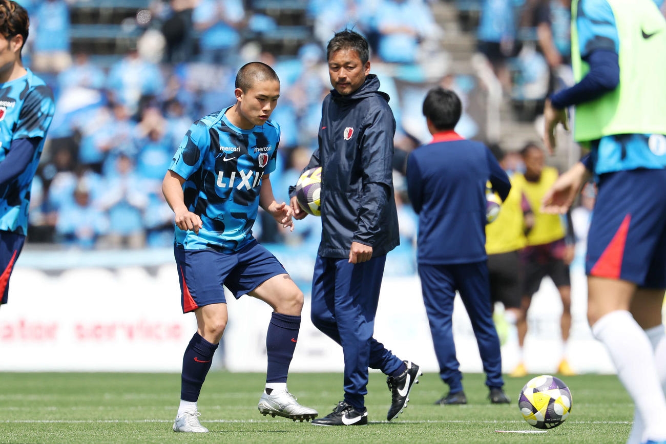 横浜FC対鹿島　試合前、鹿島柳沢コーチ（右）が見つめる中、ウオーミングアップする吉田（撮影・宮地輝）